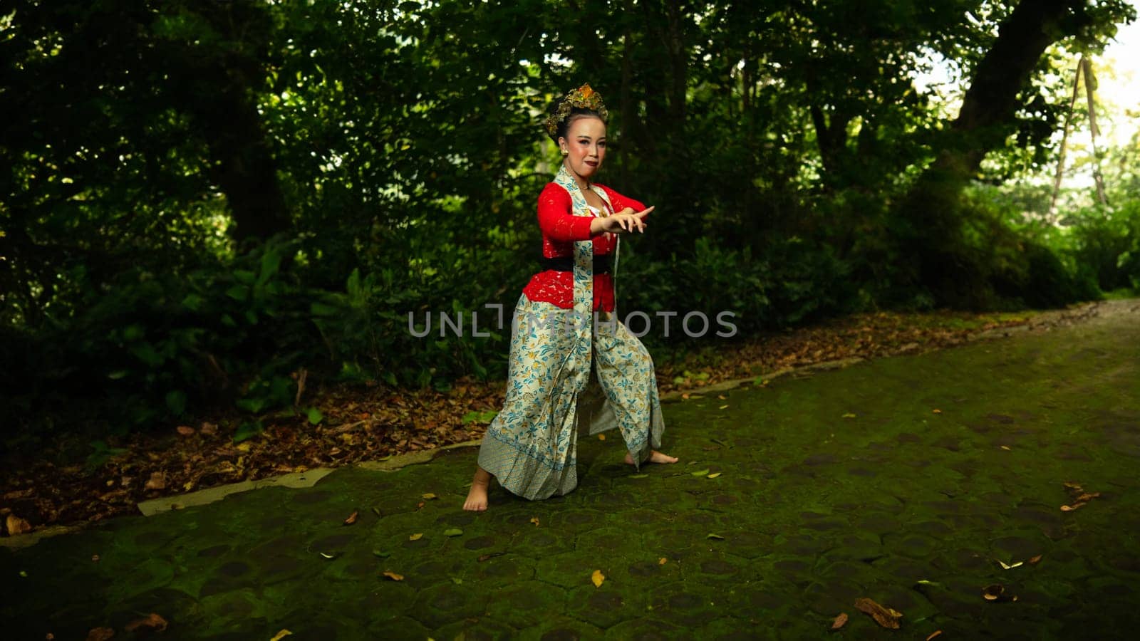a traditional Sundanese dancer wearing a red costume which is the identity of a stunning and impressive dancer when in the forest in the afternoon