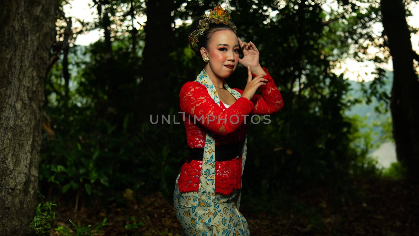 a Balinese dancer wearing a red costume which becomes a visual attraction for the audience with the beauty of the dance performed in the forest in the afternoon
