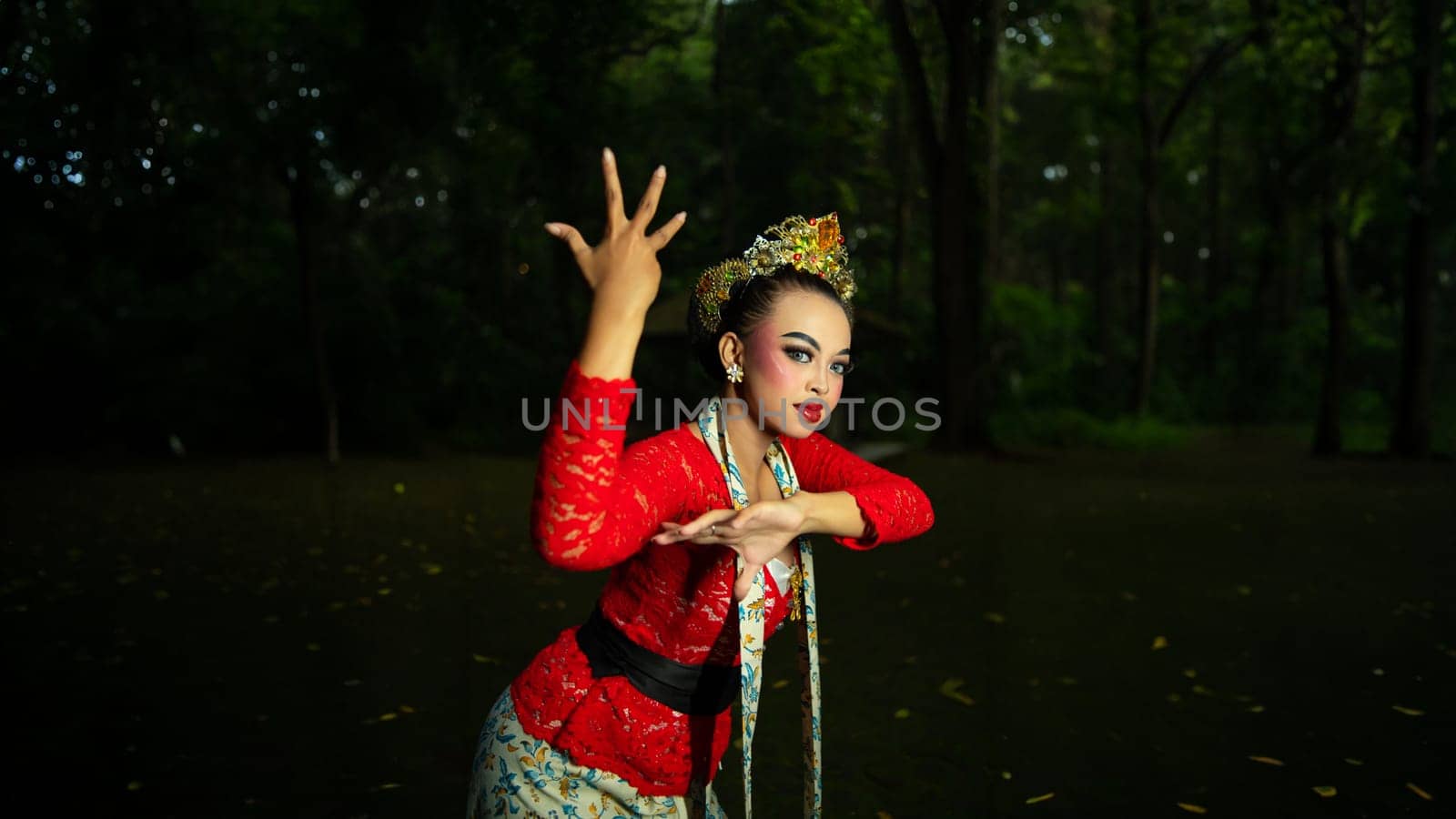 a Balinese dancer wearing a red costume which becomes a visual attraction for the audience with the beauty of the dance performed in the forest in the afternoon