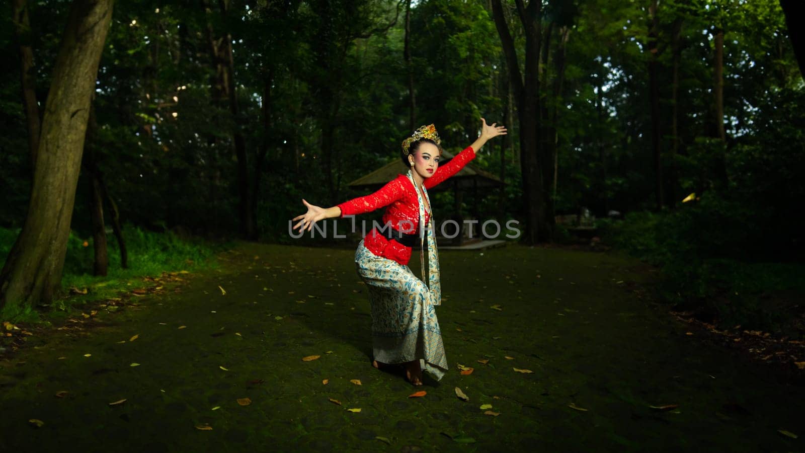 a Balinese dancer wearing a red costume which becomes a visual attraction for the audience with the beauty of the dance performed in the forest in the afternoon
