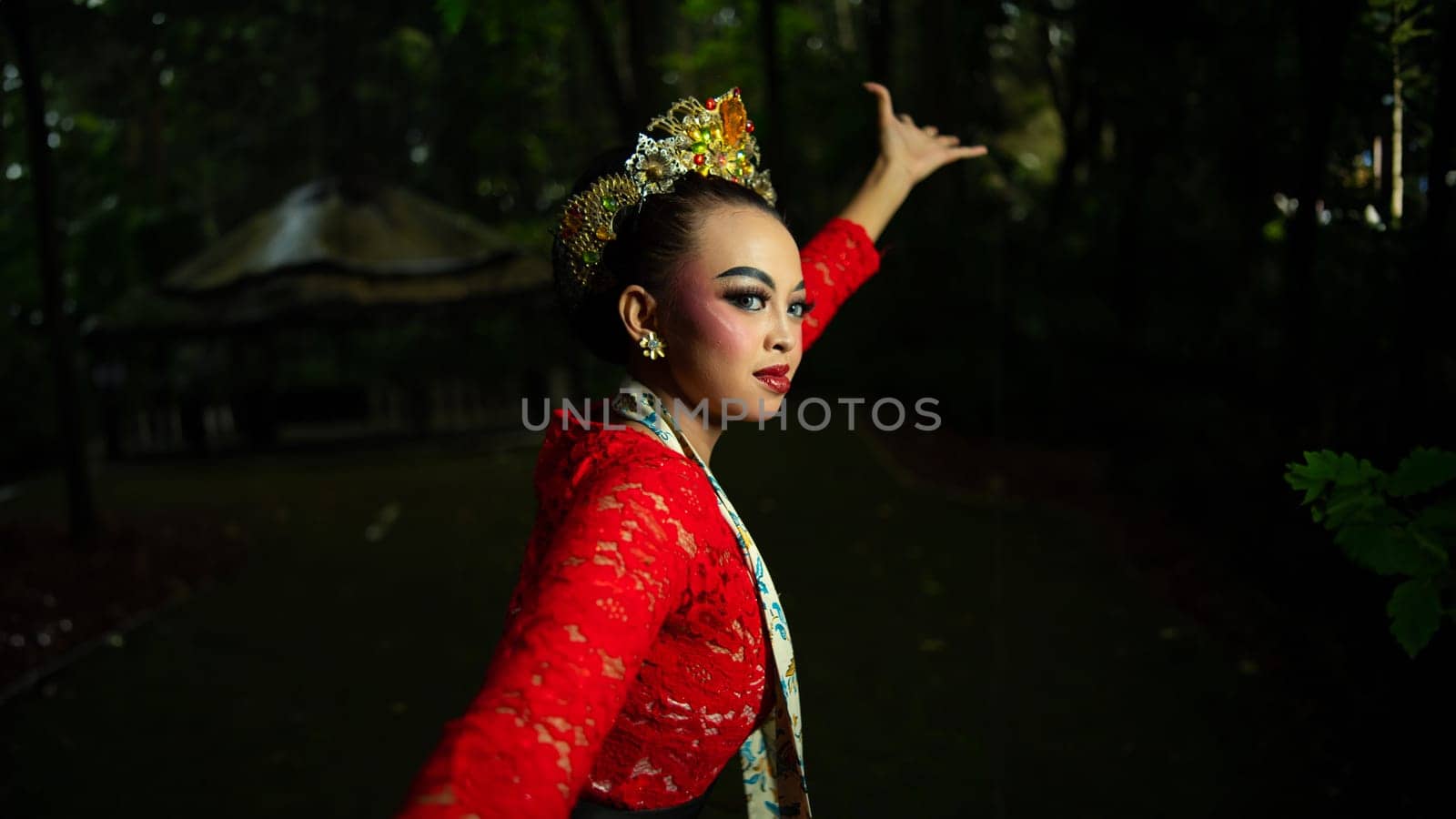 A traditional Javanese dancer wears jewelry on a red costume such as bracelets and necklaces to add to the impression of luxury when dancing in the forest in the morning
