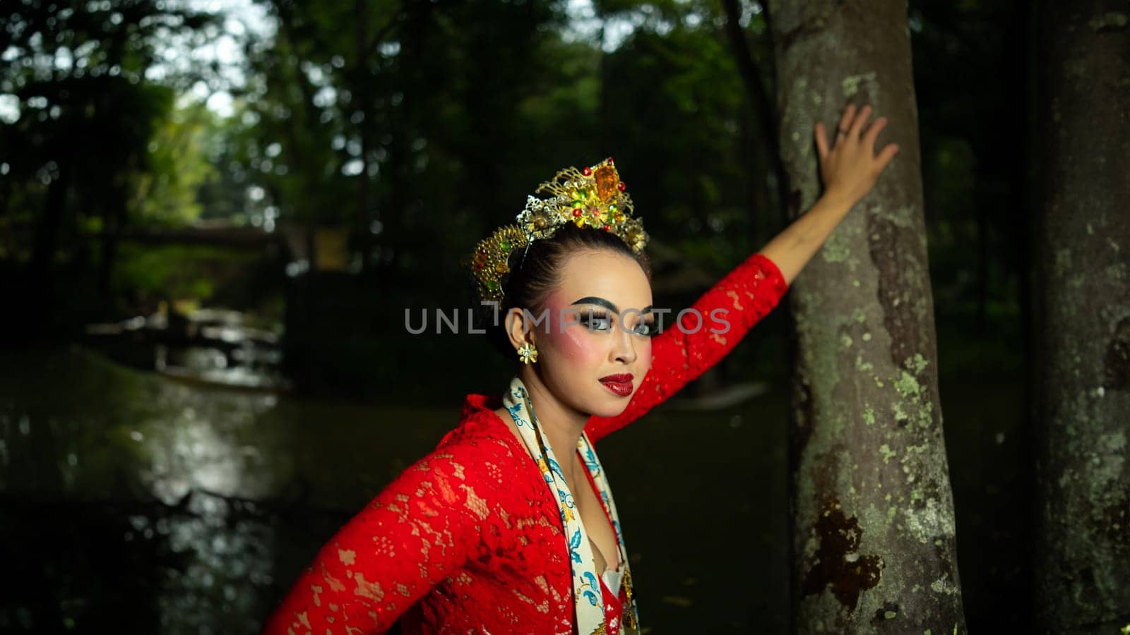 A traditional Javanese dancer wears jewelry on a red costume such as bracelets and necklaces to add to the impression of luxury when dancing in the forest in the morning