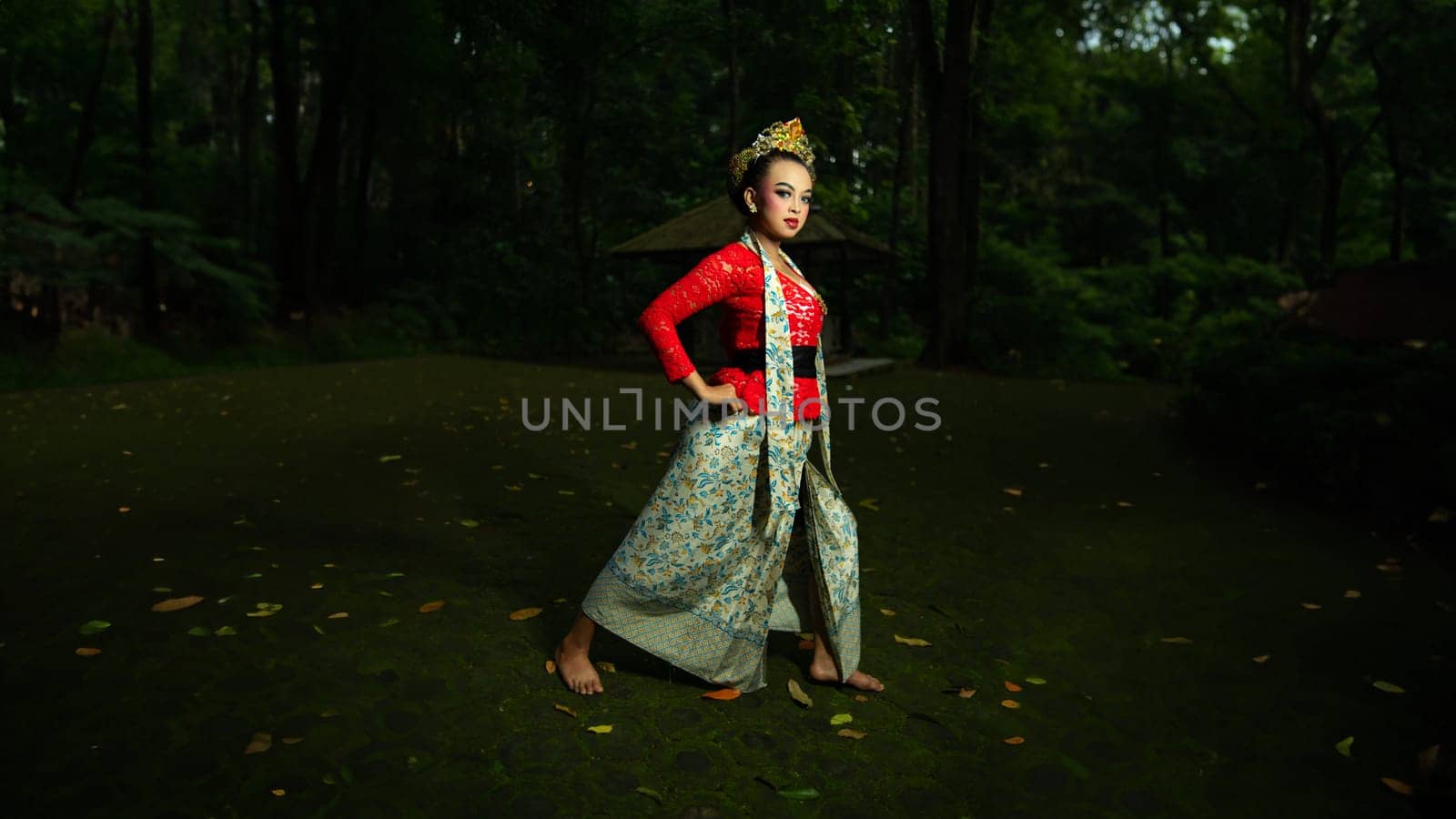 A traditional Javanese dancer wears jewelry on a red costume such as bracelets and necklaces to add to the impression of luxury when dancing in the forest in the morning
