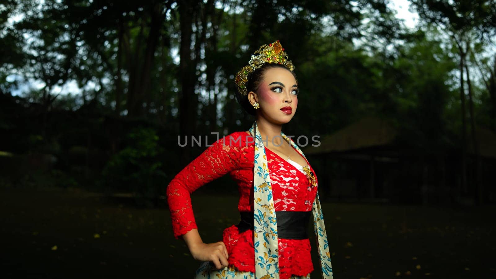 A traditional Javanese dancer wears jewelry on a red costume such as bracelets and necklaces to add to the impression of luxury when dancing in the forest in the morning