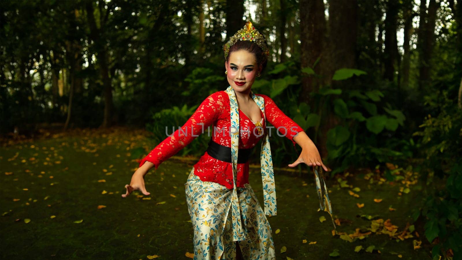 a traditional Sundanese dancer wearing a red costume that reflects the beauty and richness of Indonesian culture while in the forest in the morning