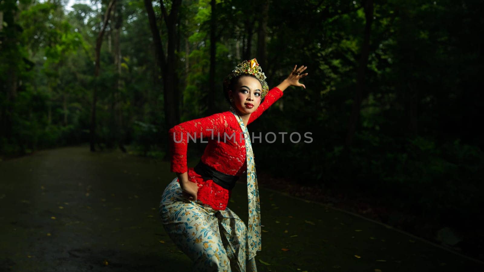 Indonesian traditional dancers wear red costumes with gold crown decorations which are very majestic when in the forest in the morning
