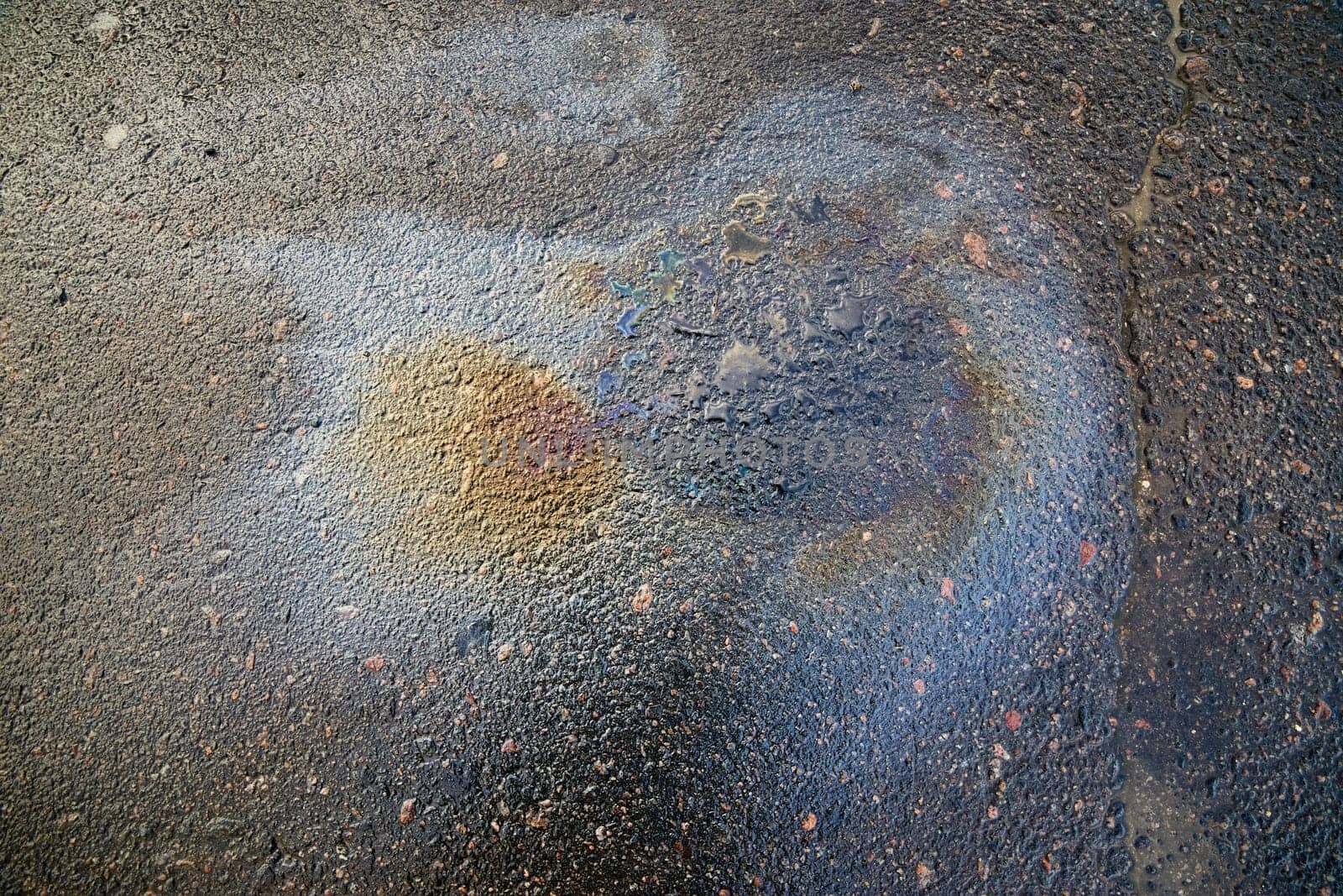 Brightly colored oil stain forming an abstract pattern on asphalt