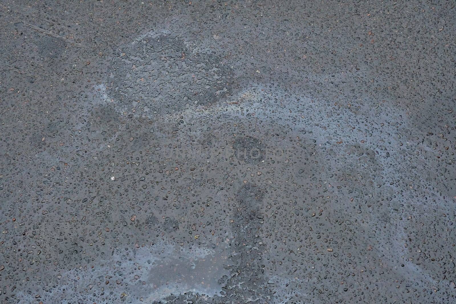 Colored texture of oil products on asphalt in bright sunlight after rain. Oil dripped from the car engine onto the road