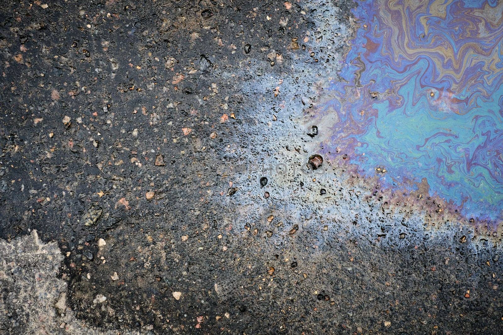 A top view of a shimmering film of oil or gasoline on wet pavement