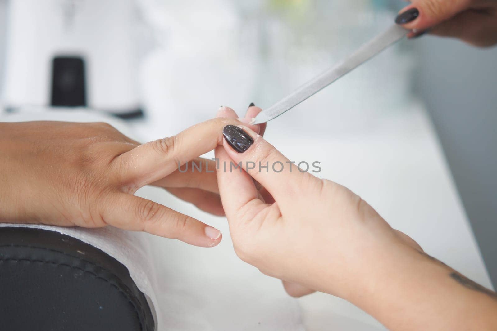 In a salon, a skilled nail technician meticulously applies a beautiful manicure with care