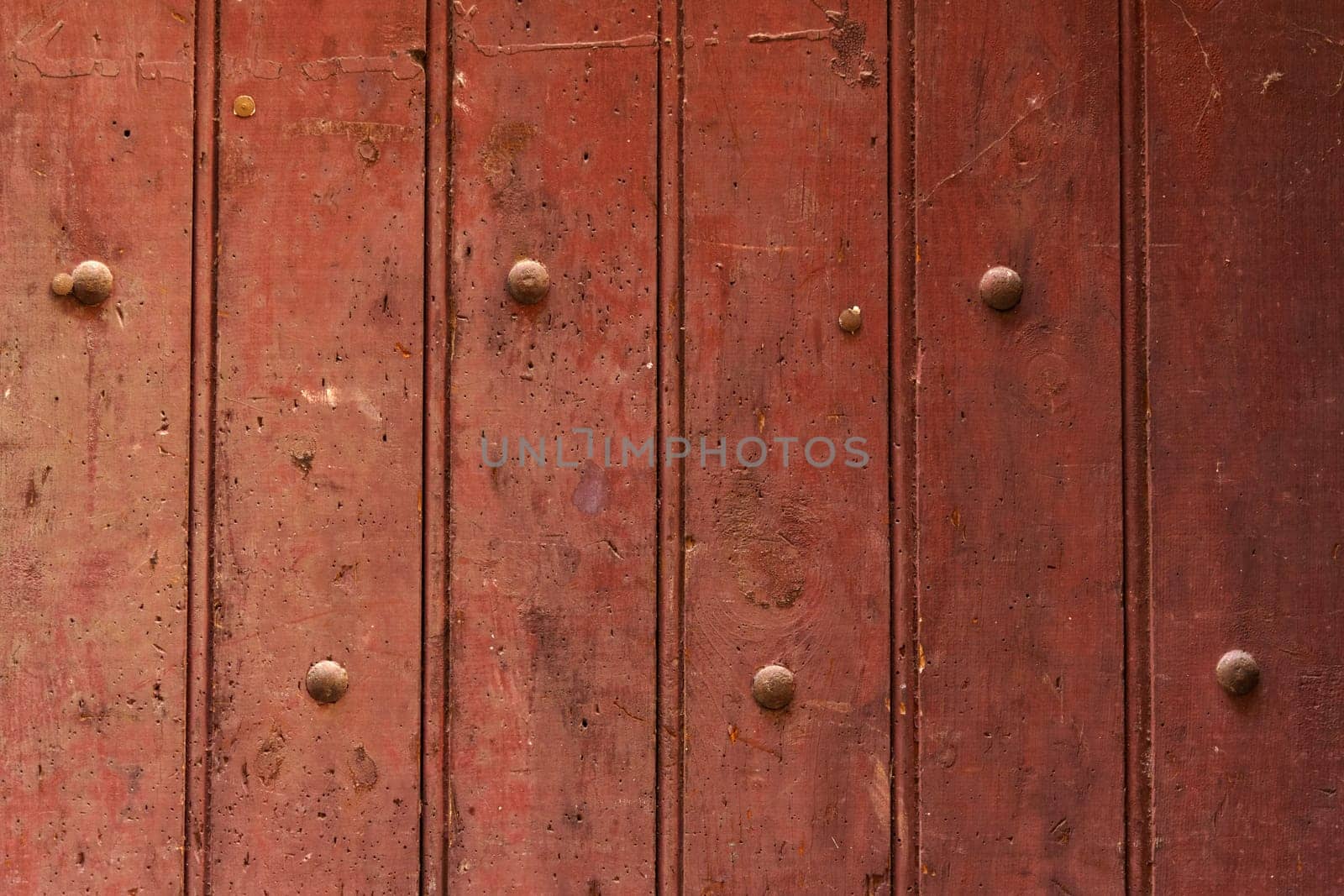 Texture of a wooden board painted red with rivets. Close-up.