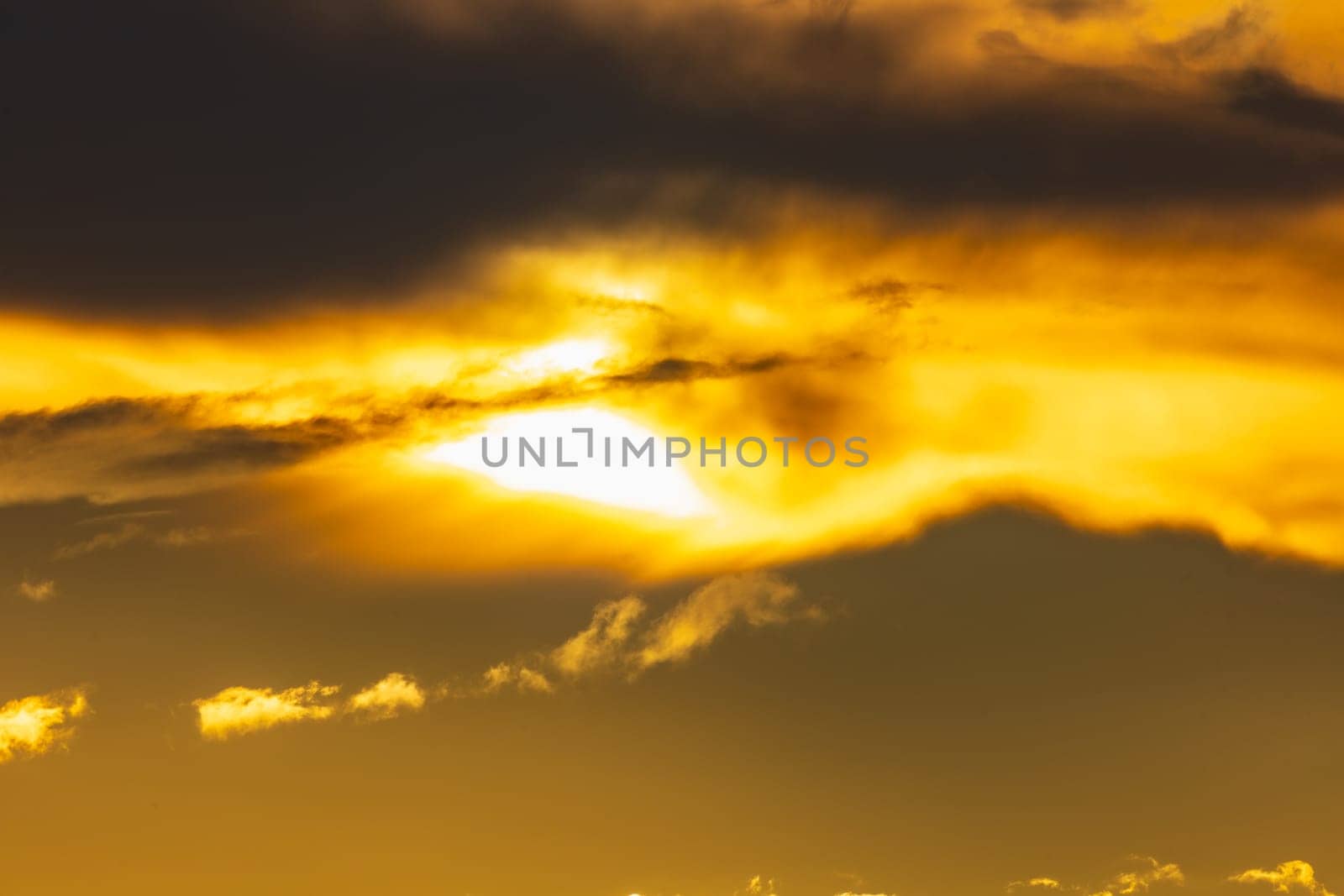 Beautiful cloudy yellow sunset with gigantic sun over big fields and trees seen by 600mm camera lens 