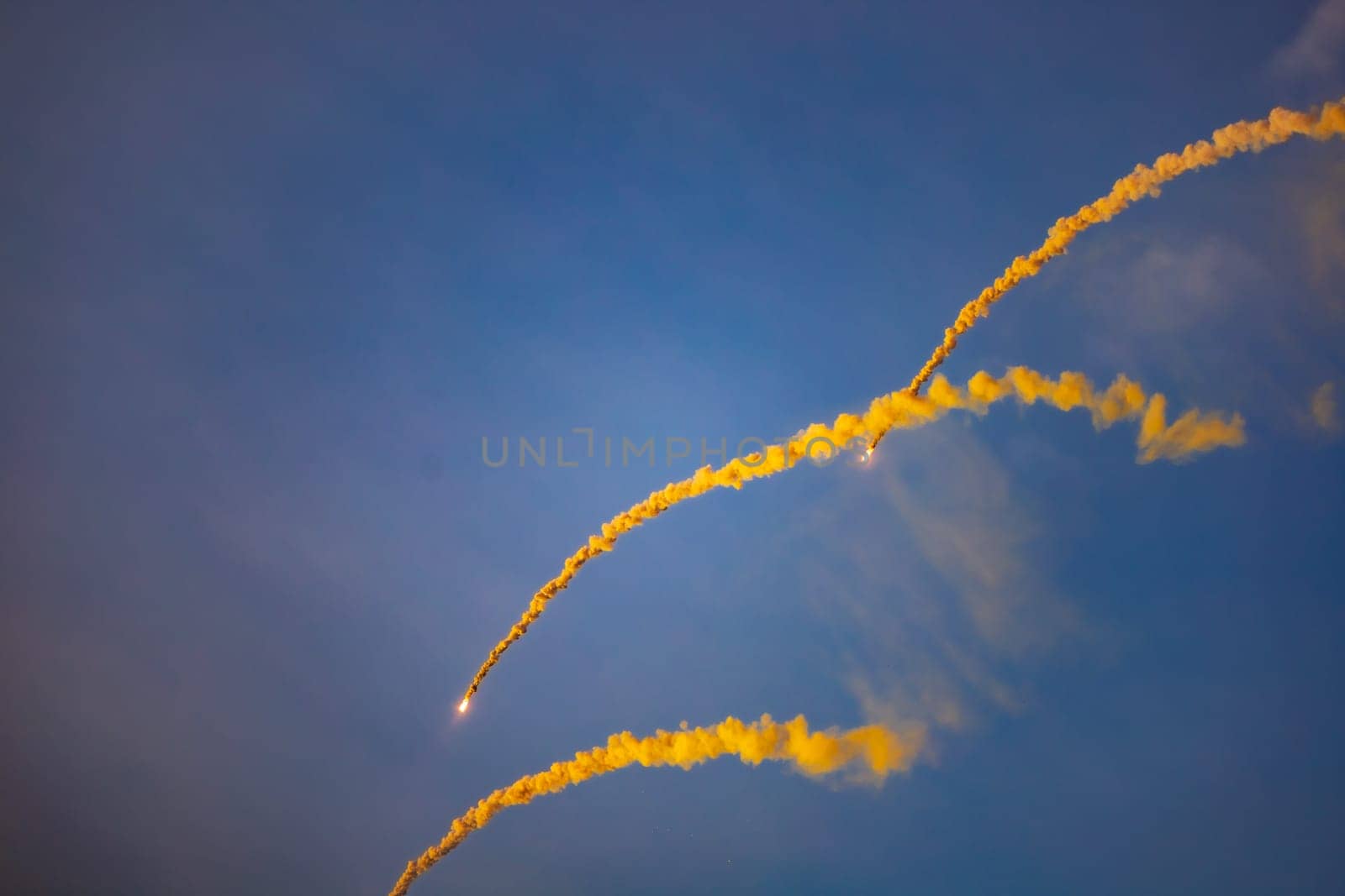 Beautifully glowing flares with a lot of smoke flying on the blue sky at golden hour before sunset