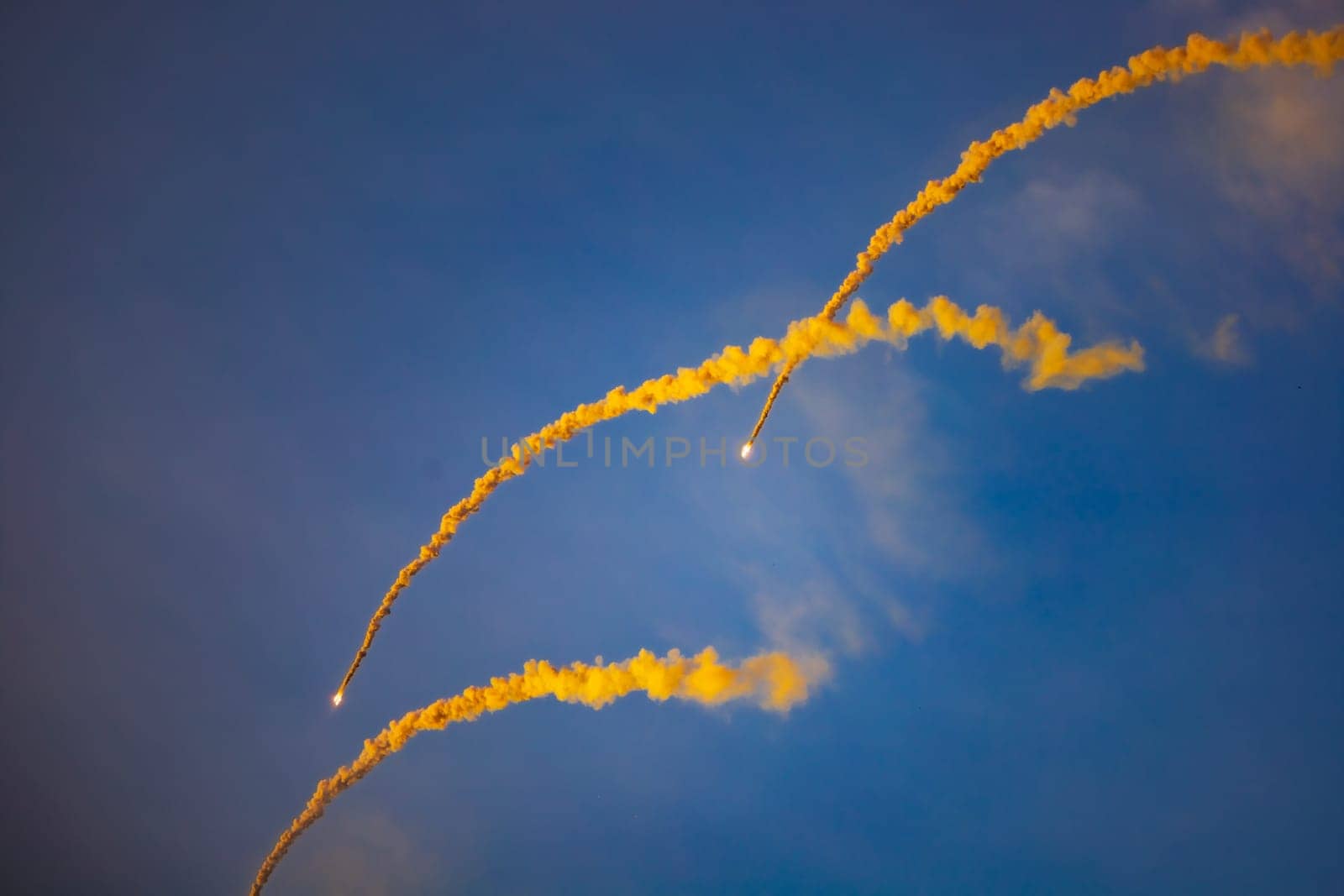 Beautifully glowing flares with a lot of smoke flying on the blue sky at golden hour before sunset