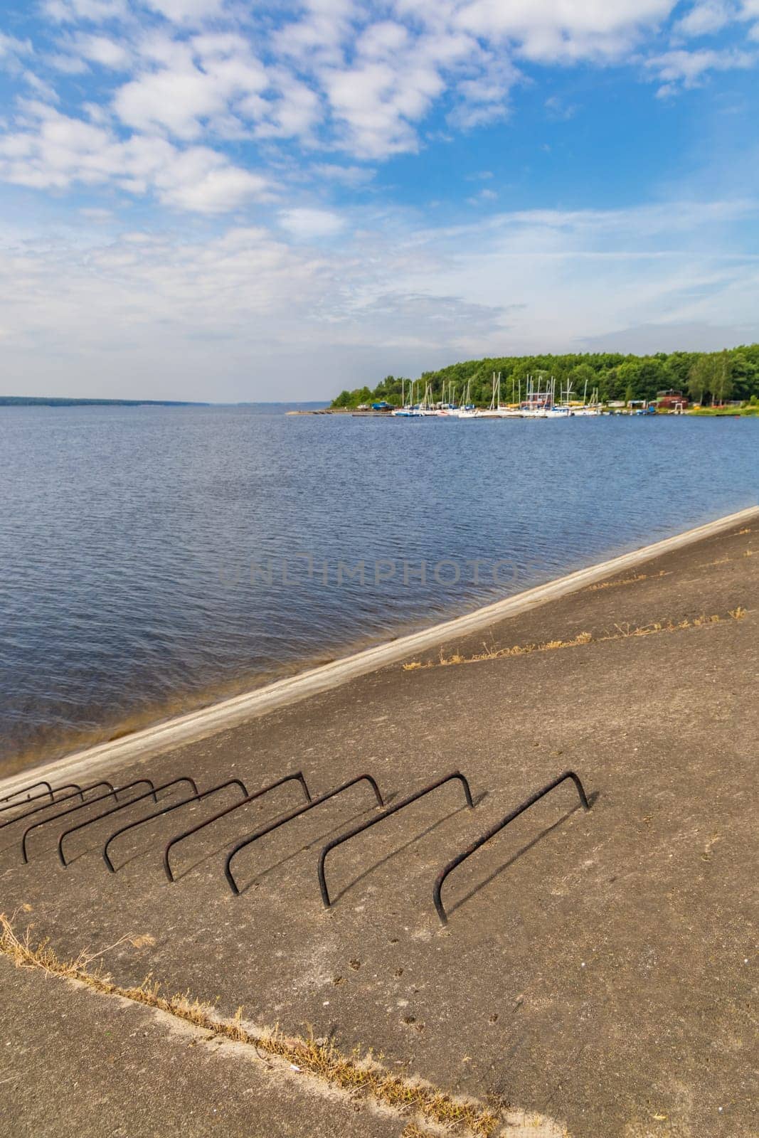 Small bay behind small local harbor at the coast of big lake next to water dame and road