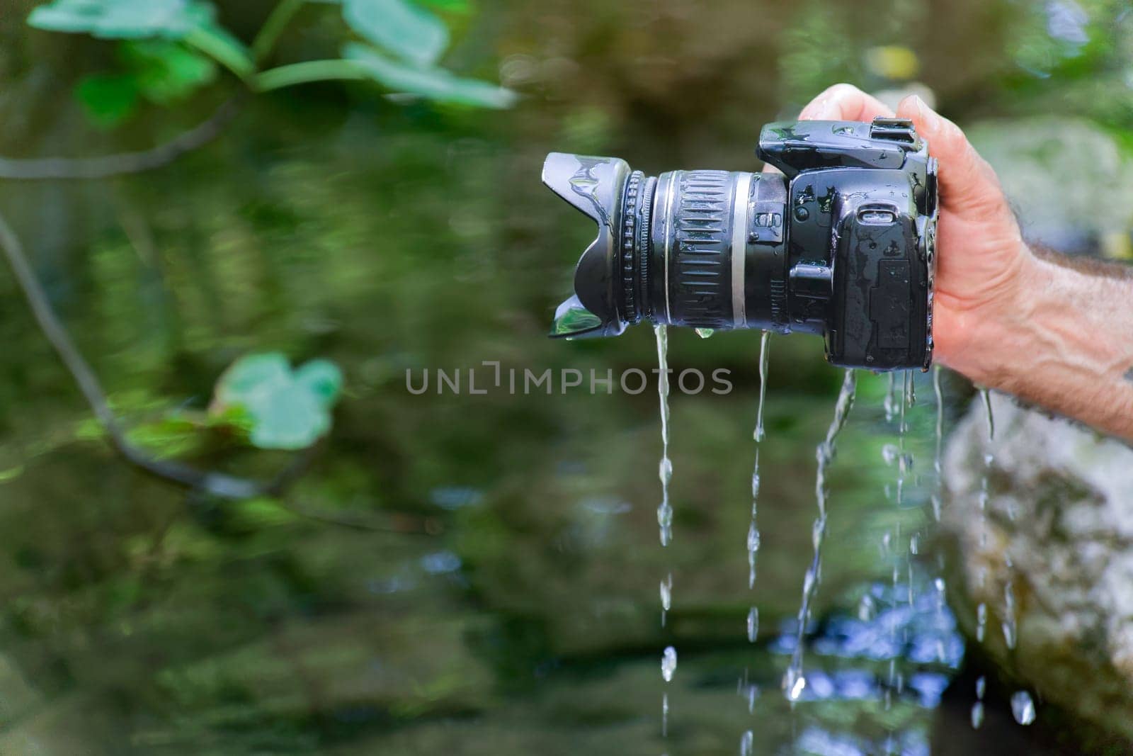 man pulls his reflex camera out of the river flooded with water by joseantona