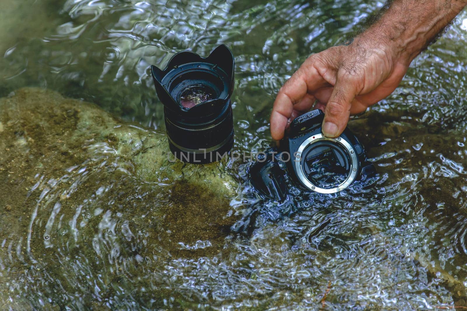 man cleans his reflex camera sensor in river water by joseantona