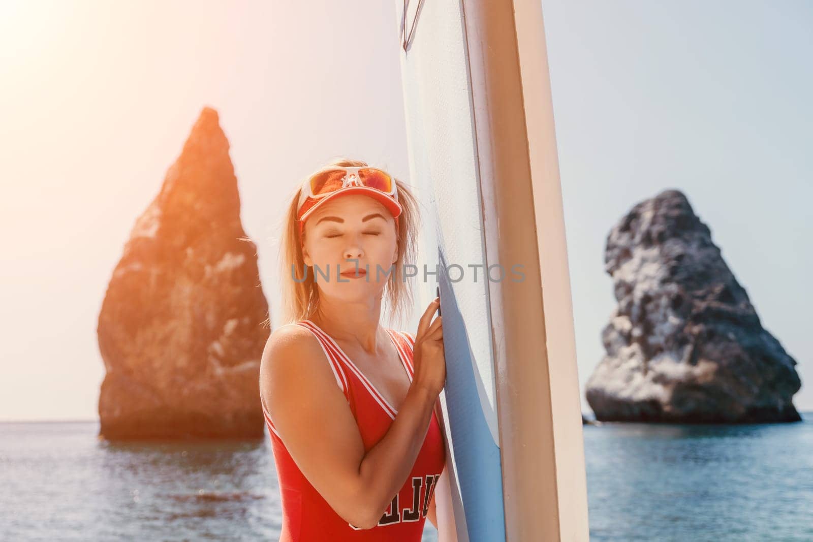 Woman sea sup. Close up portrait of happy young caucasian woman with blond hair looking at camera and smiling. Cute woman portrait in red bikini posing on sup board in the sea by panophotograph