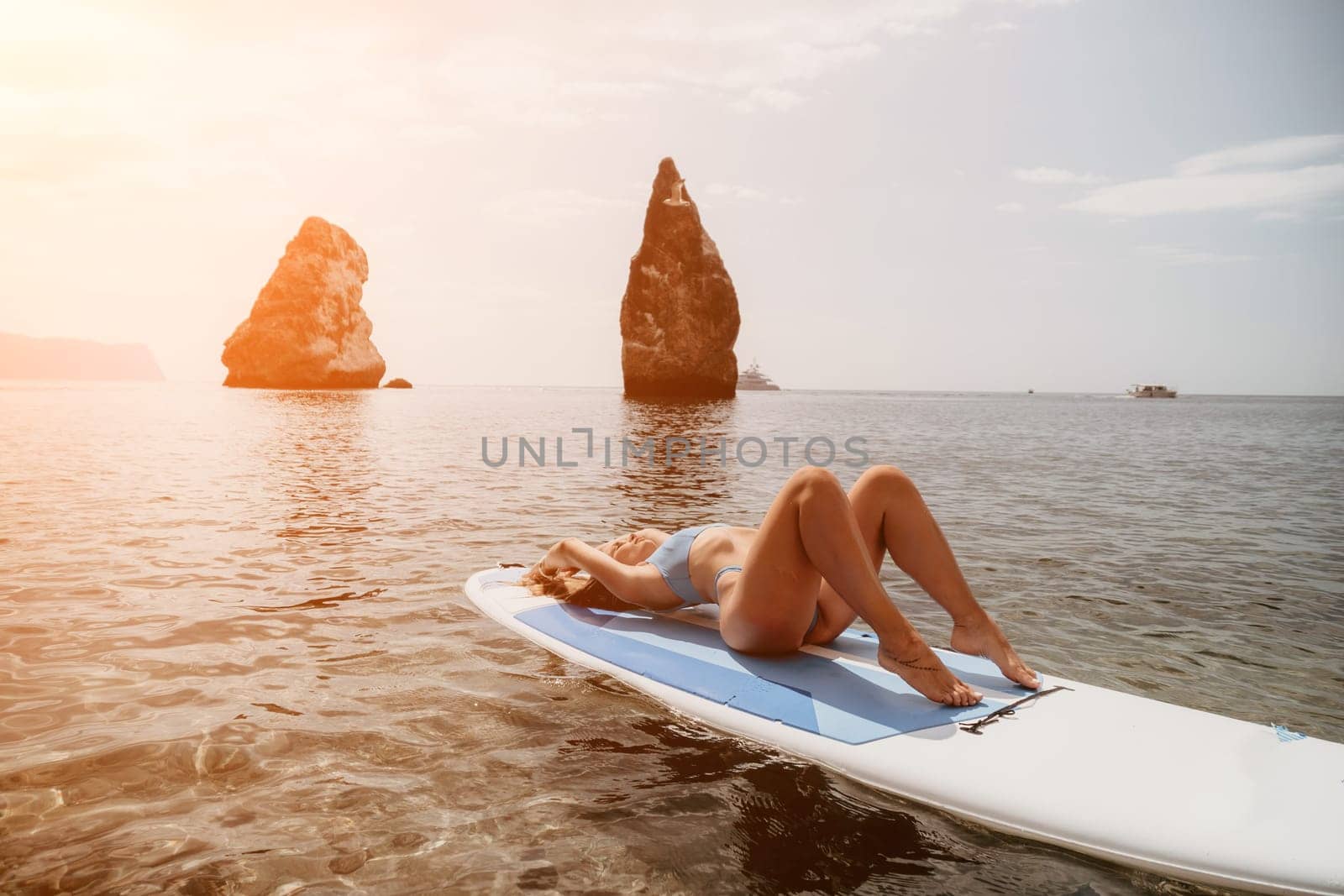 Close up shot of beautiful young caucasian woman with black hair and freckles looking at camera and smiling. Cute woman portrait in a pink bikini posing on a volcanic rock high above the sea