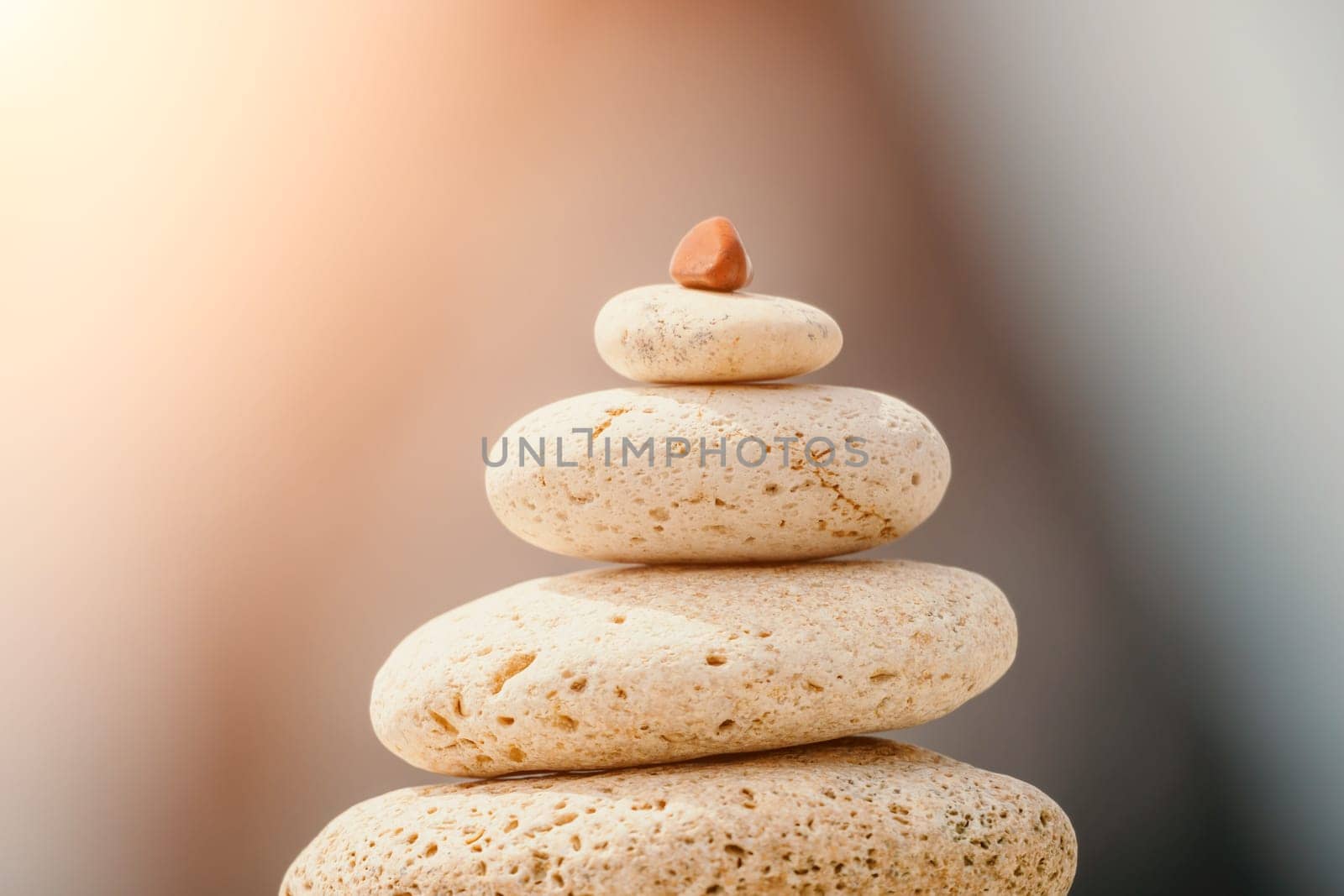 Pyramid stones on the seashore with warm sunset on the sea background. Happy holidays. Pebble beach, calm sea, travel destination. Concept of happy vacation on the sea, meditation, spa, calmness.