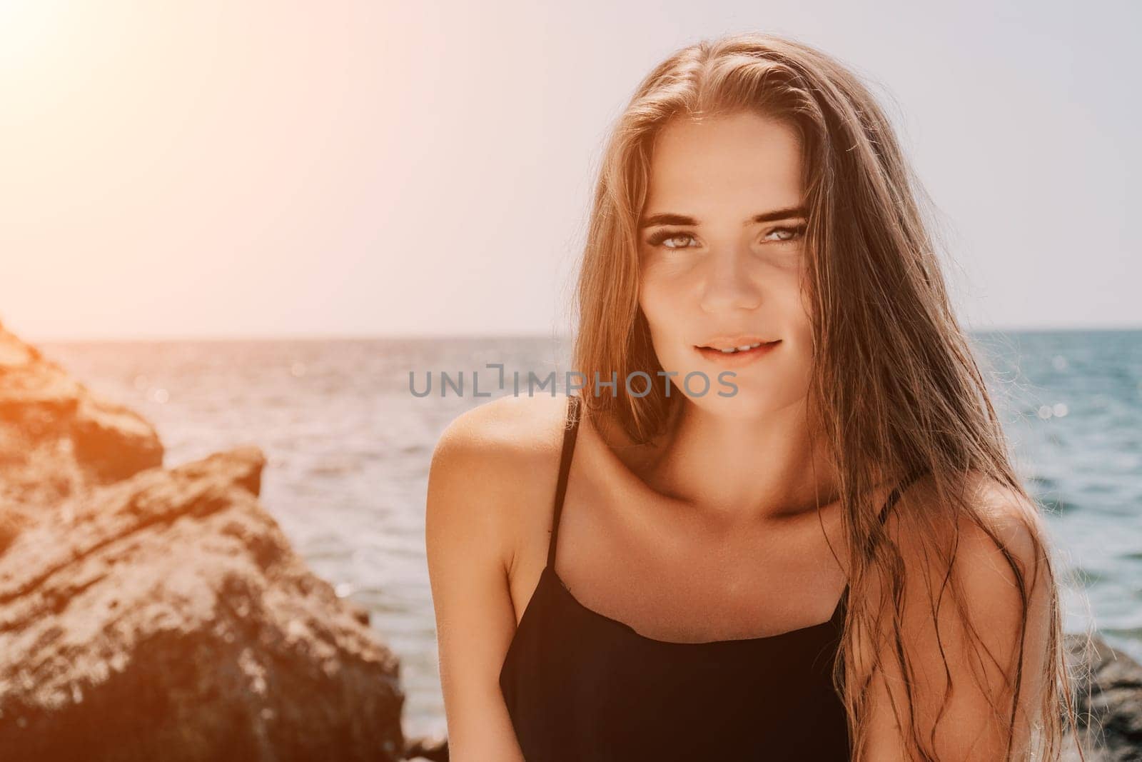 Woman summer travel sea. Happy tourist in hat enjoy taking picture outdoors for memories. Woman traveler posing on the beach at sea surrounded by volcanic mountains, sharing travel adventure journey by panophotograph