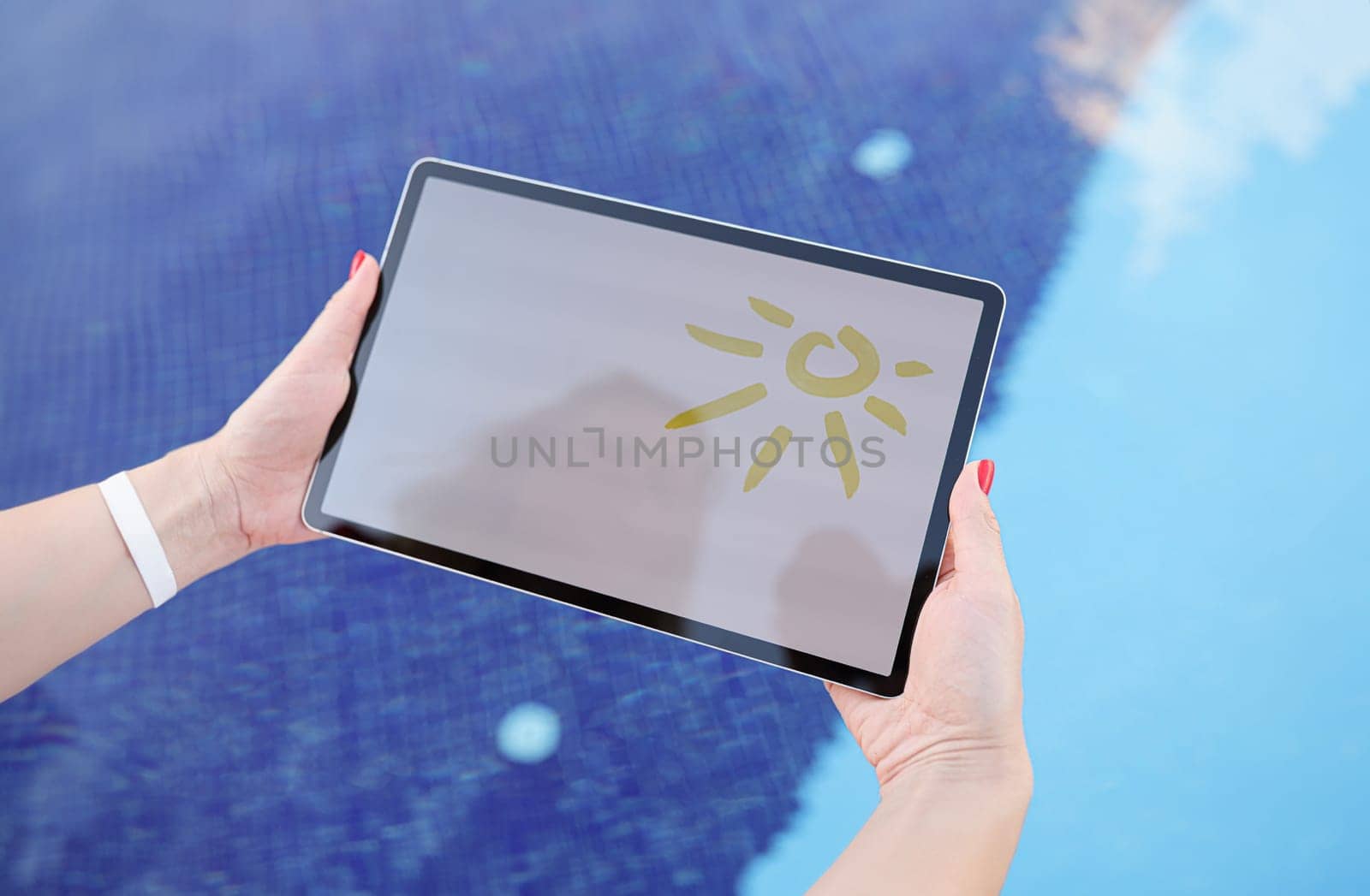 Female hands hold tablet with drawn sun and white screen above pool. Advertising travel banner free space for text