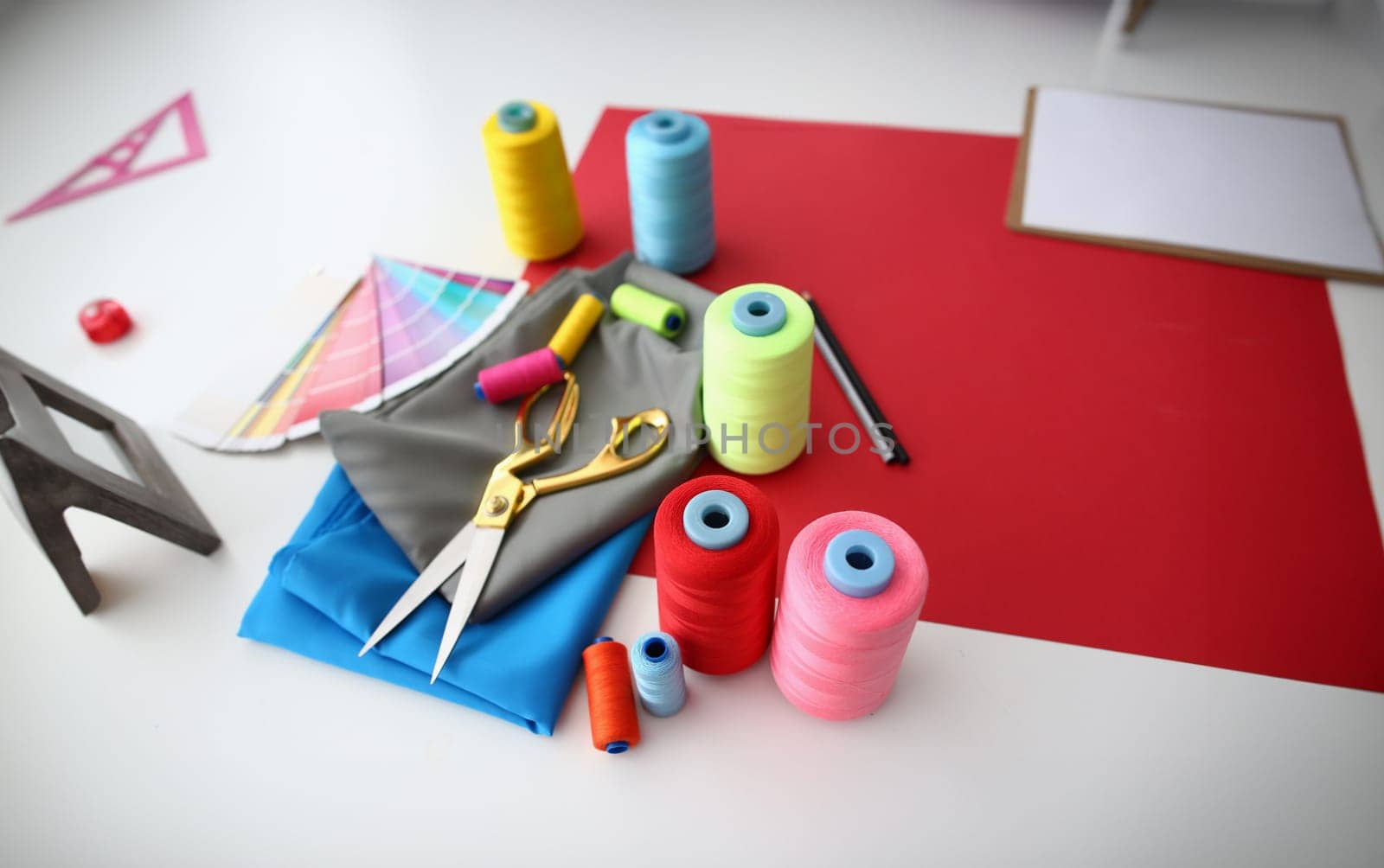 Multicolored fabric threads and scissors in atelier at workplace. Accessories for tailoring concepts