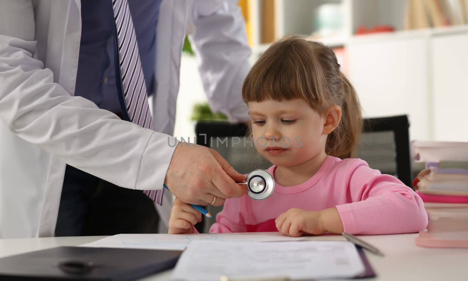 Hands of pediatrician doctor examining small child with stethoscope. Pediatrics and medicine healthcare concept