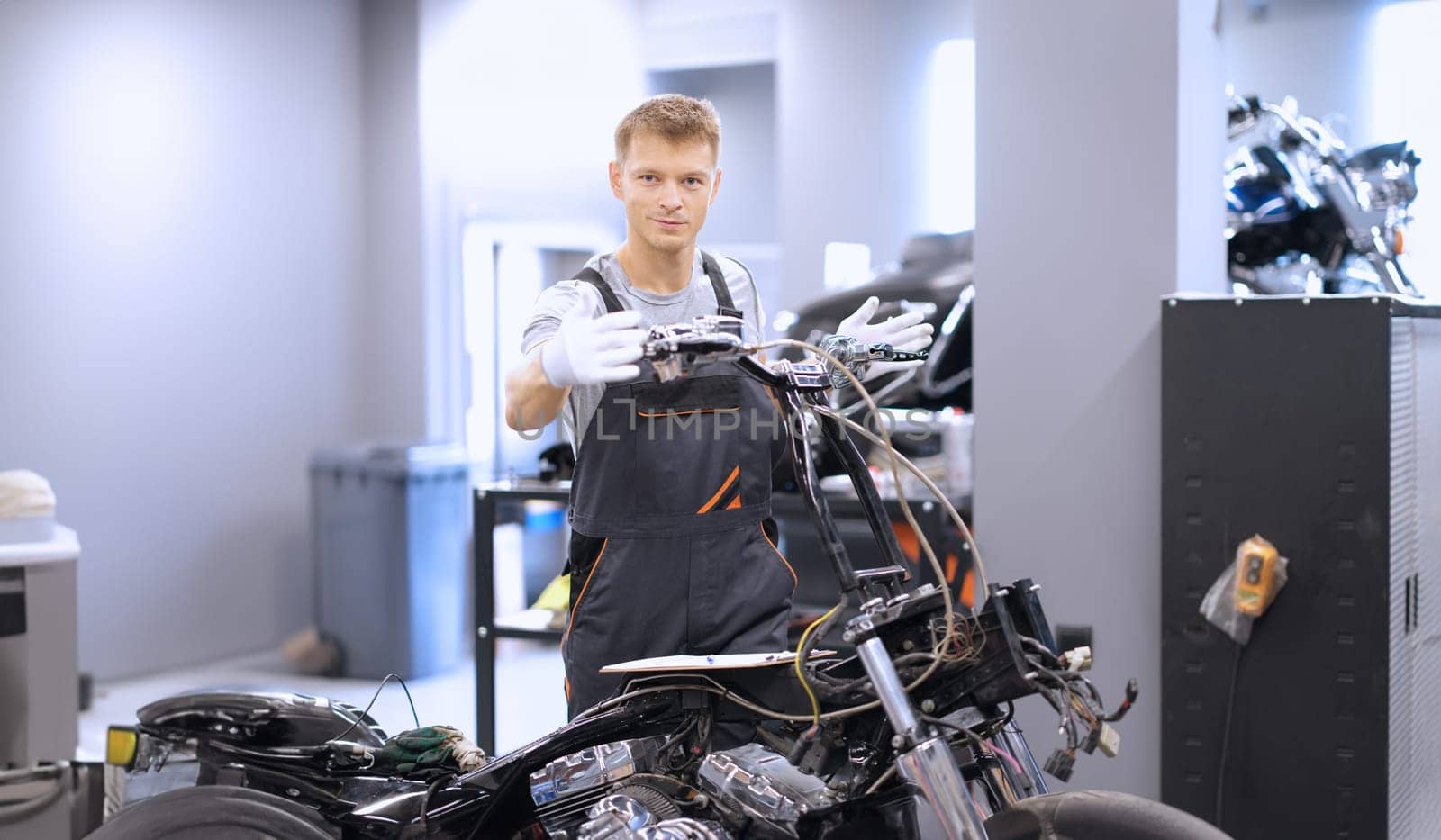 Auto mechanic checks technical condition of motorcycle in workshop. Vehicle service station services concept