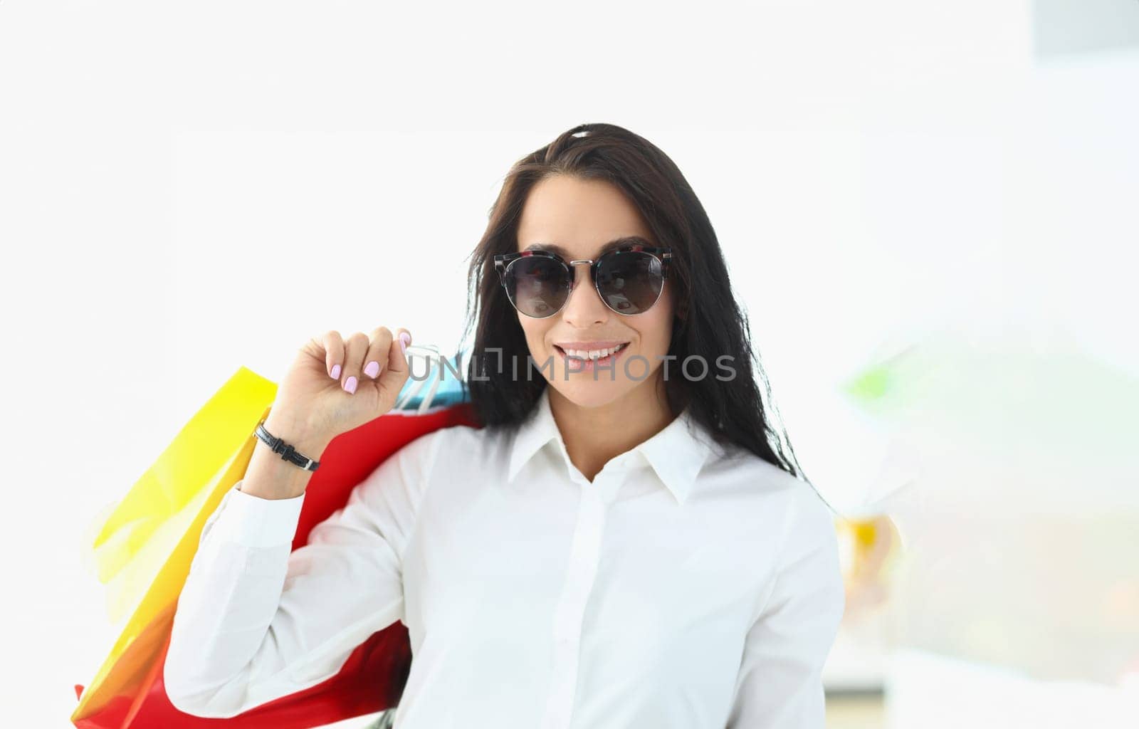 Portrait of astonished charming brunette holding shopping bags with glasses by kuprevich