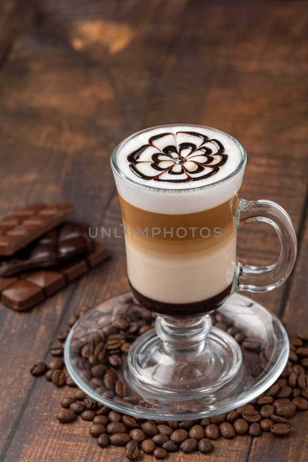 Multilayer coffee latte in glass cup on wooden table by Sonat