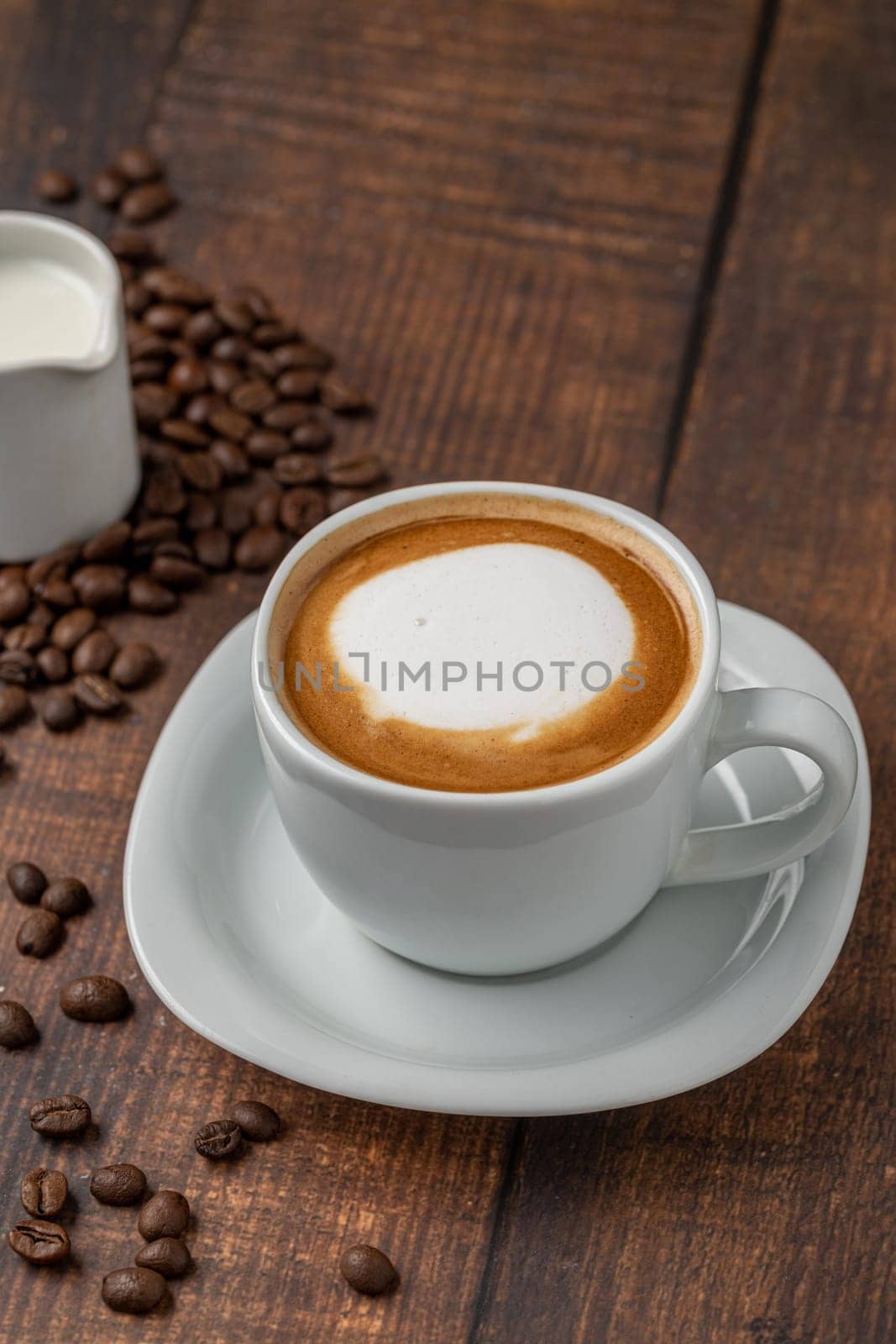 Relaxing latte coffee in white porcelain cup on wooden table by Sonat