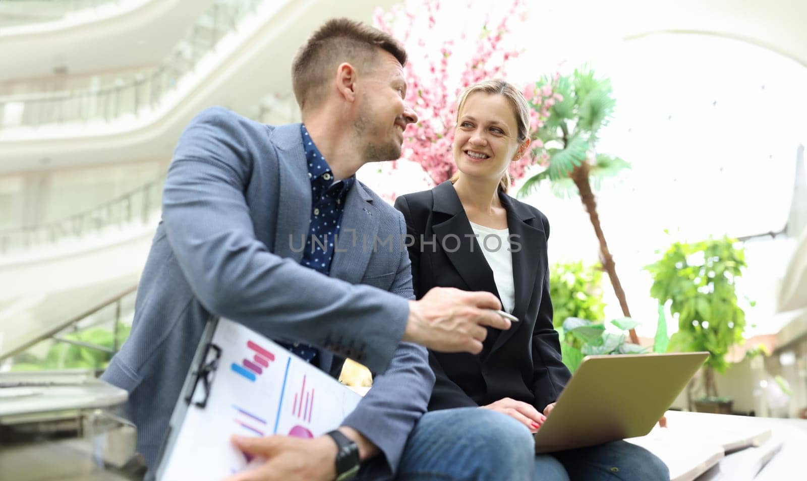 Two business happy smiling people are discussing work and development of startup. Colleagues partners communicate at work