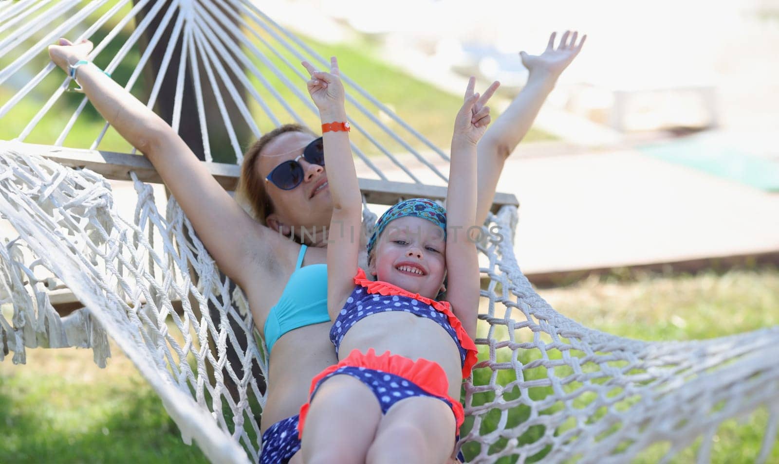 Loving family mom and daughter spend time together in summer hammock. Family happy joyful vacation in summer garden