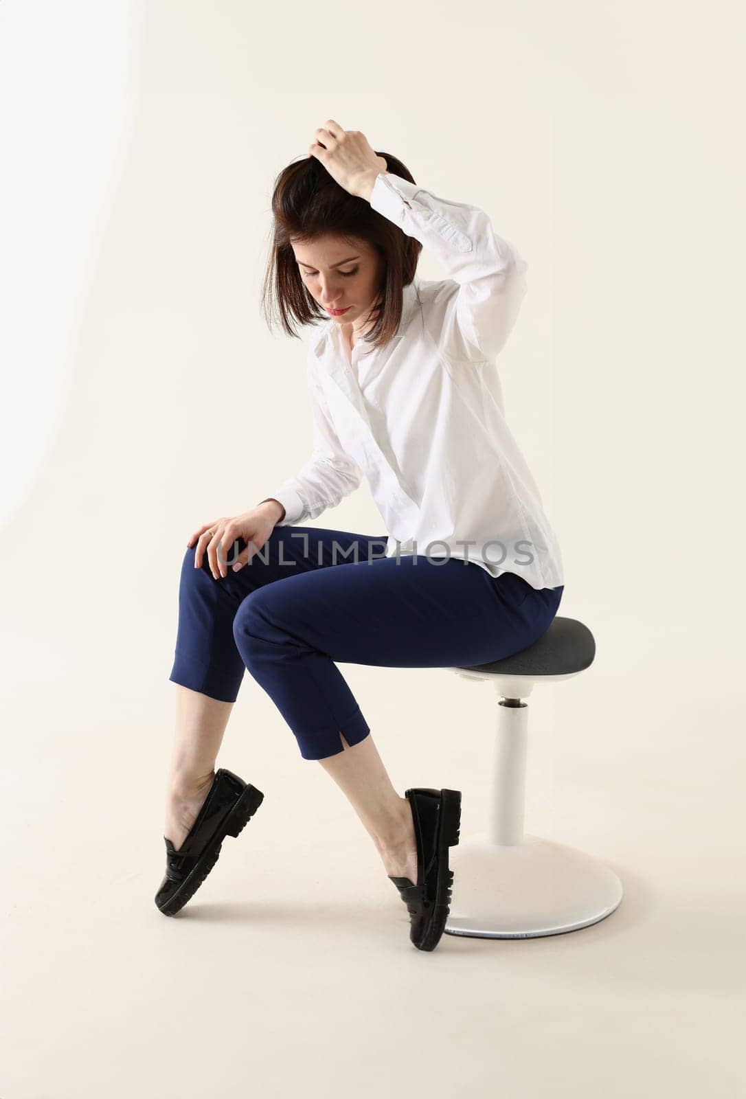 Woman in bad mood, bored and sad, sits on chair and puts hands on head. Woman in depression concept