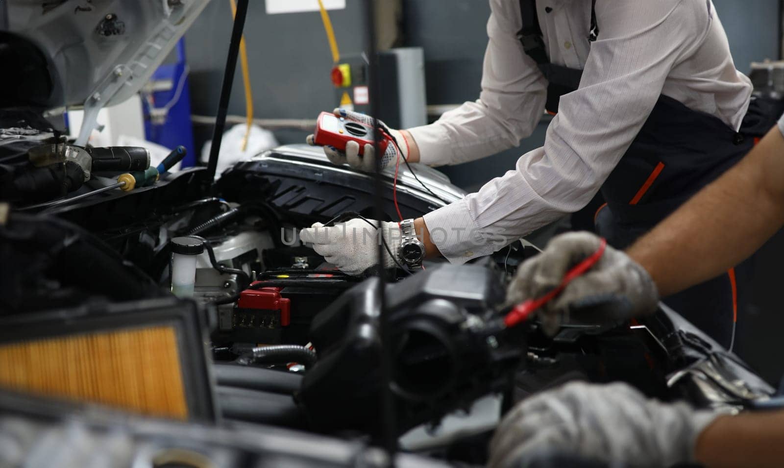Car repair technicians use voltage multimeter to work in auto repair shops. Diagnostics of car engine breakdowns