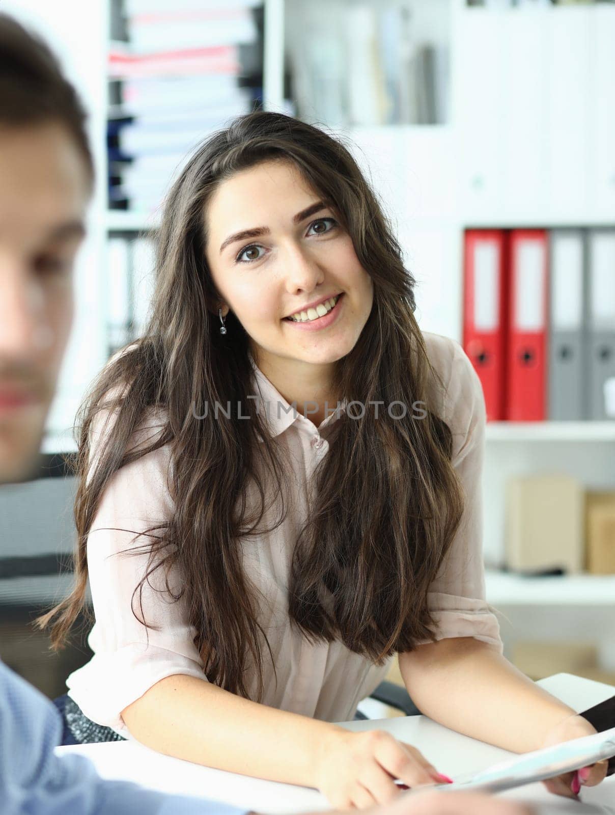 Portrait of smiling assistant at business meeting in office by kuprevich