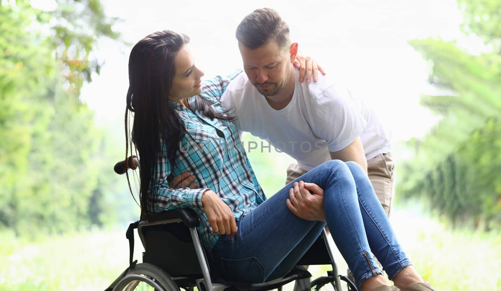 Man helps disabled woman into wheelchair closeup by kuprevich