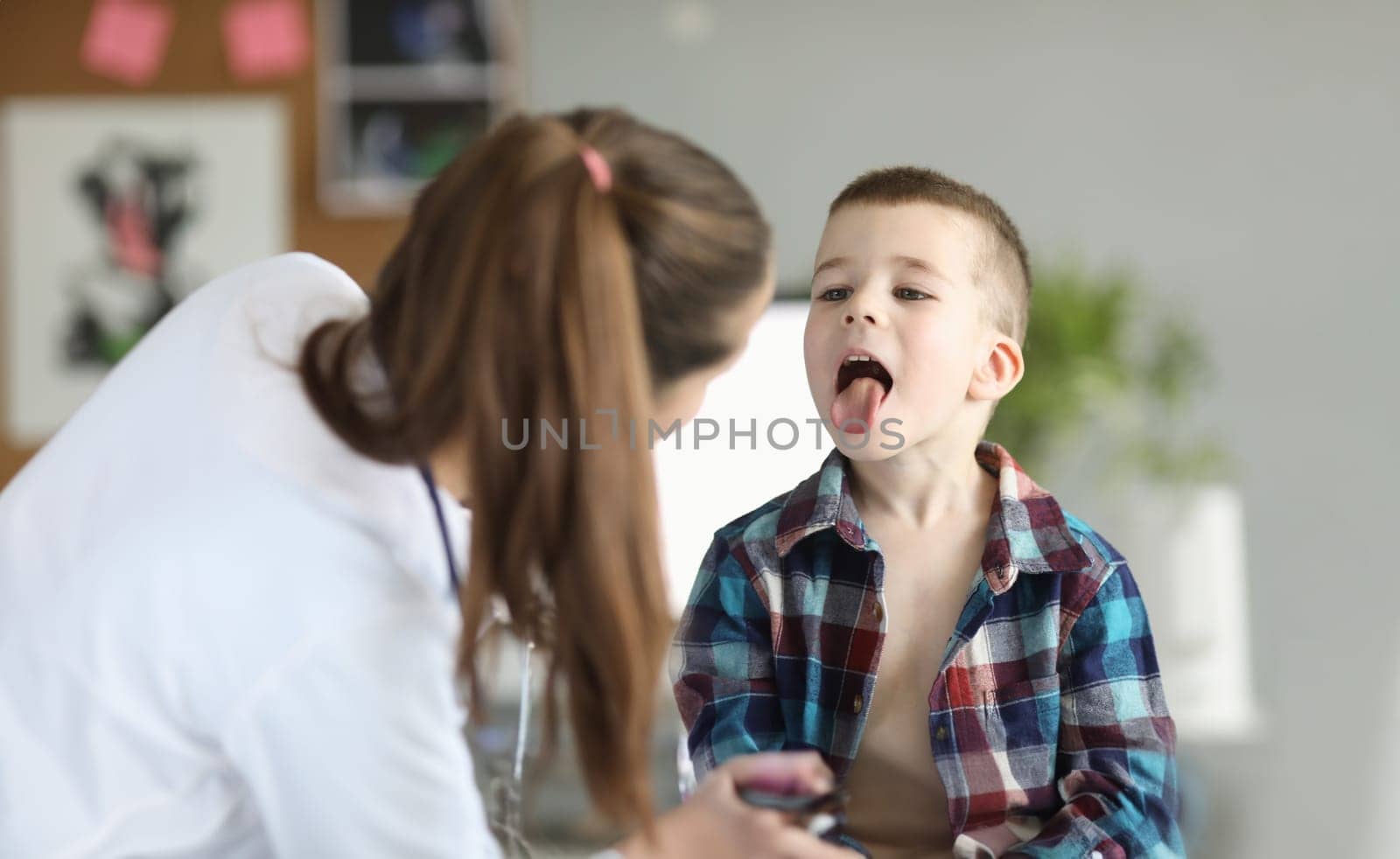 Doctor consults little boy with sore throat by kuprevich
