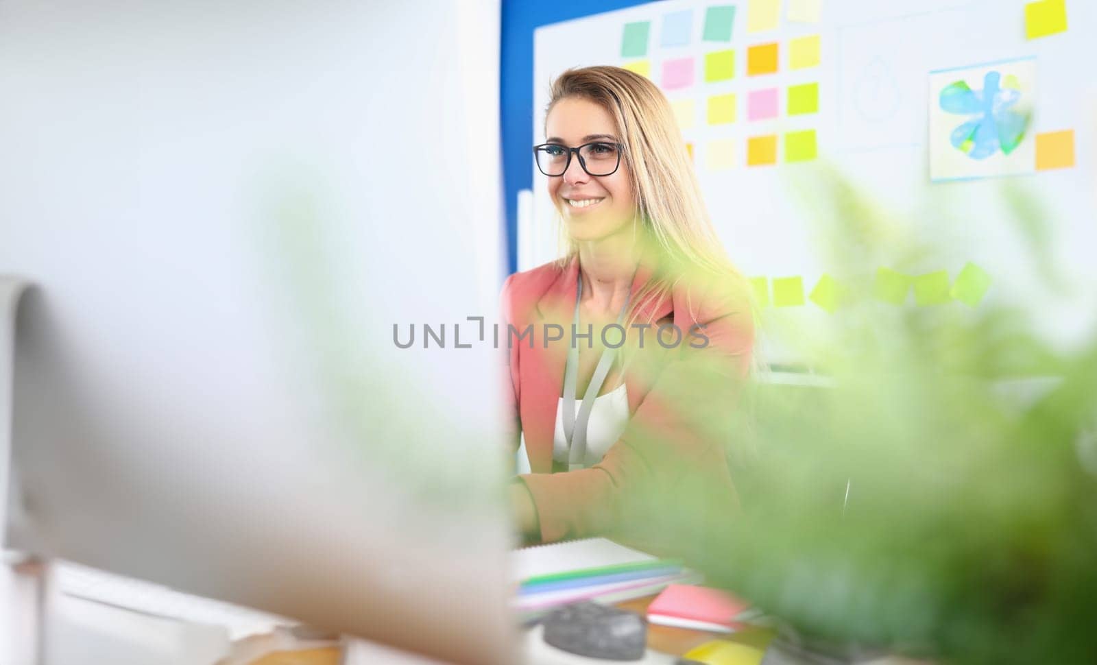 Portrait of beautiful cheerful young business woman working on laptop and laughing in office by kuprevich