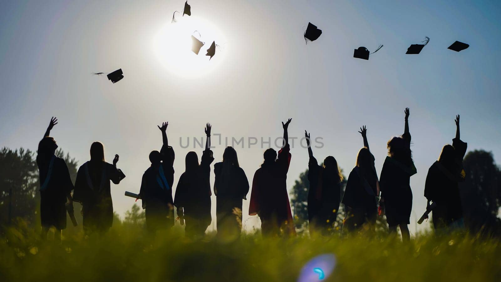 Silhouetted graduates joyfully tossing their caps into the air against a vibrant sunset, celebrating a significant milestone in their academic journey