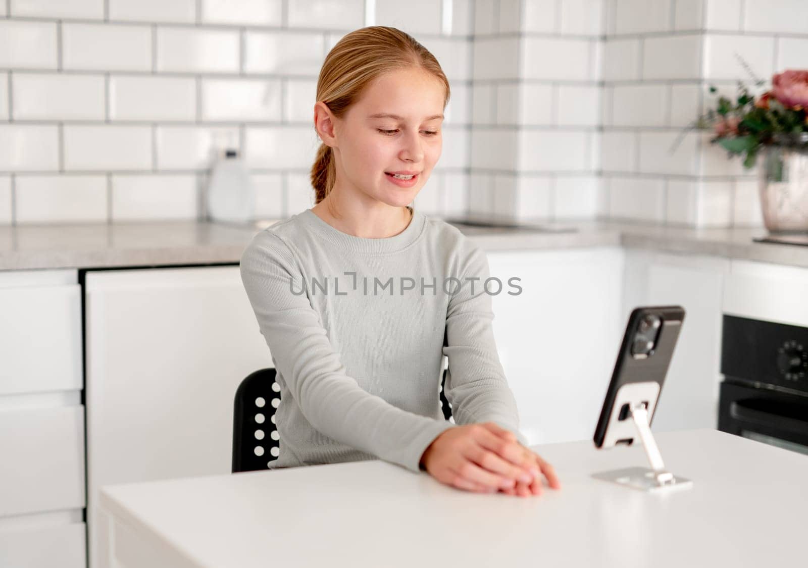Cute Little Girl Using A Smartphone For A Video Call And Online Learning At Home