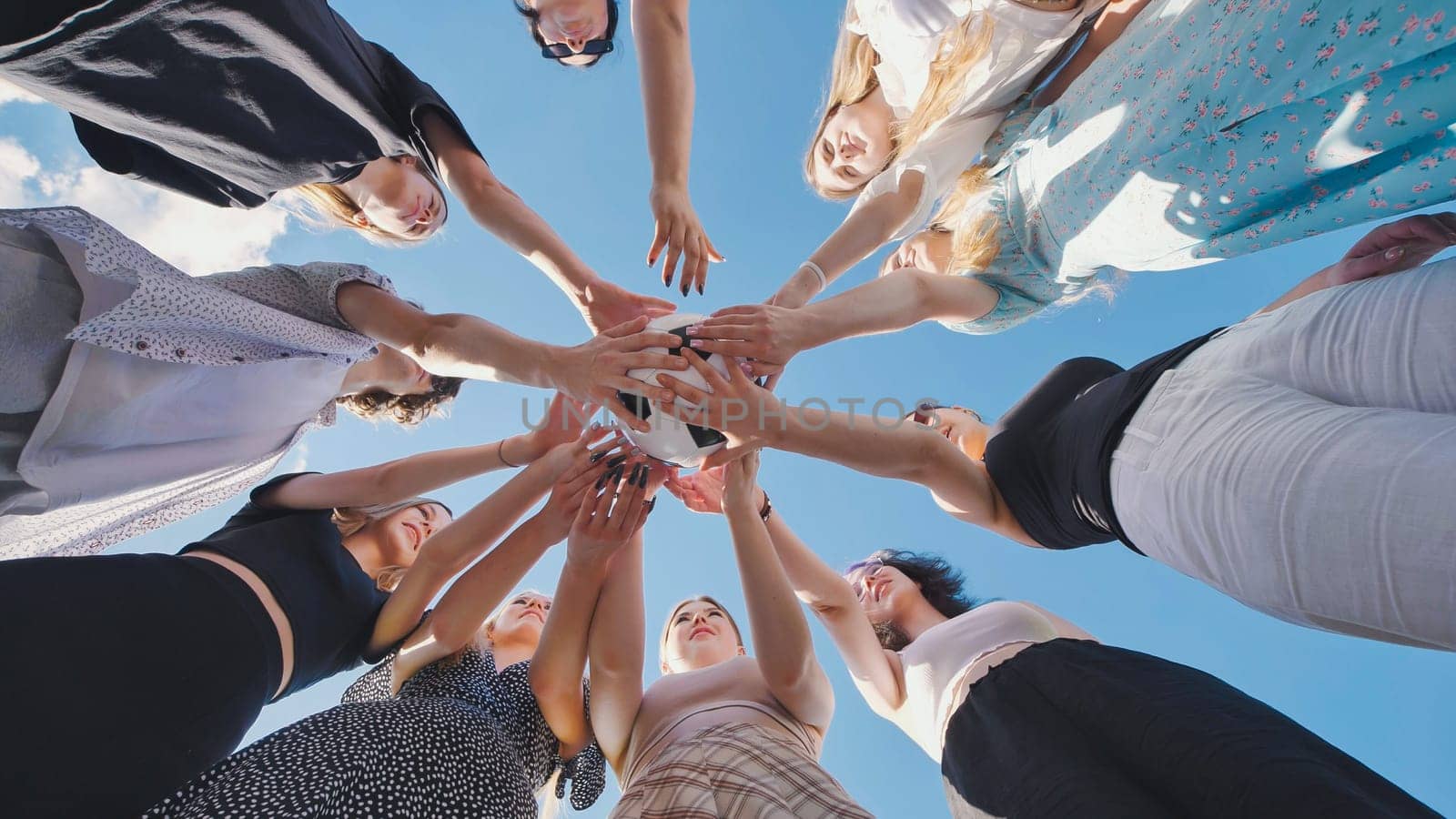 Friends join hands over a soccer ball and then toss it above them