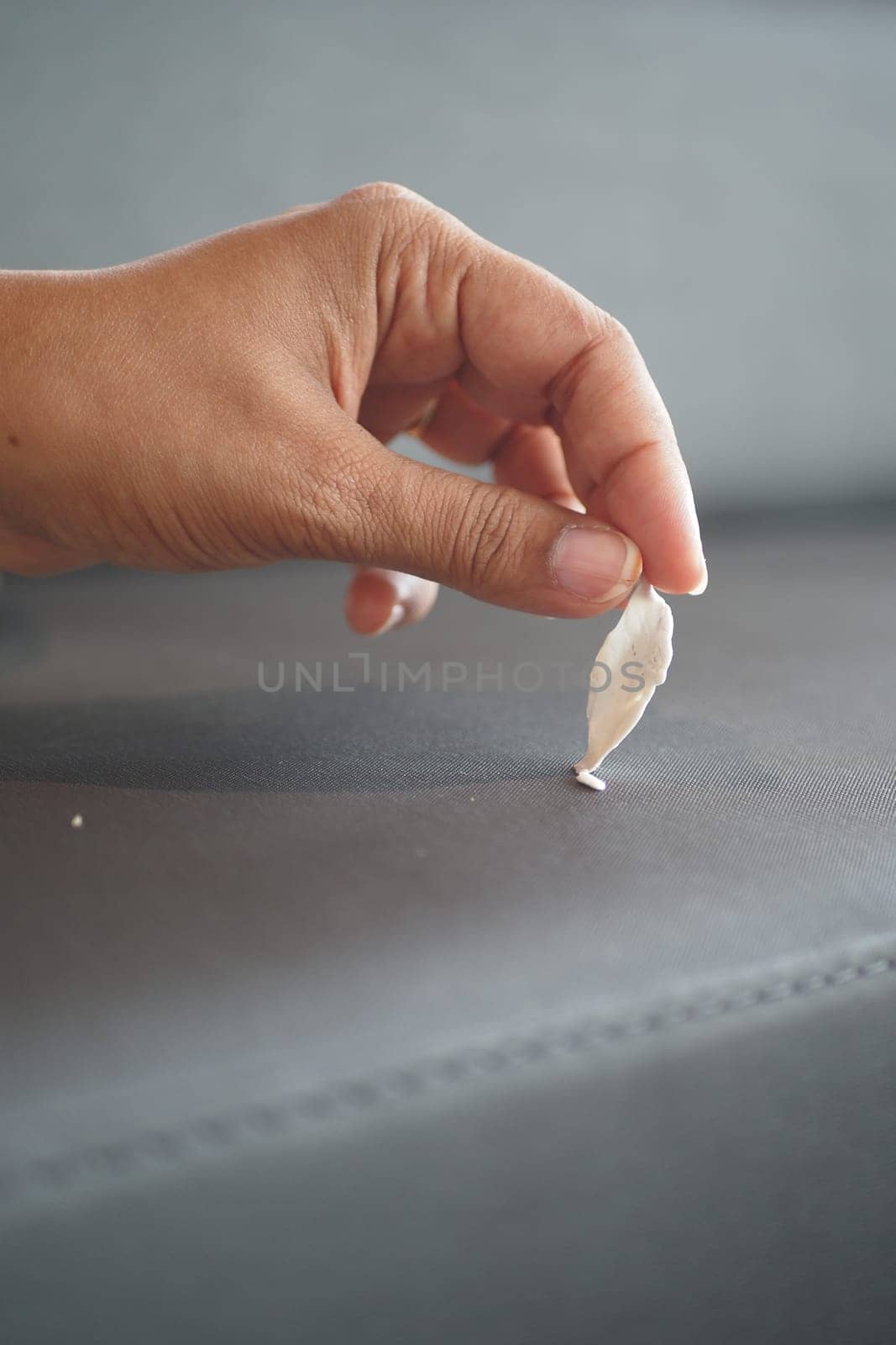 A close-up of removing stuck chewing gum from dark fabric with fingers in focus.