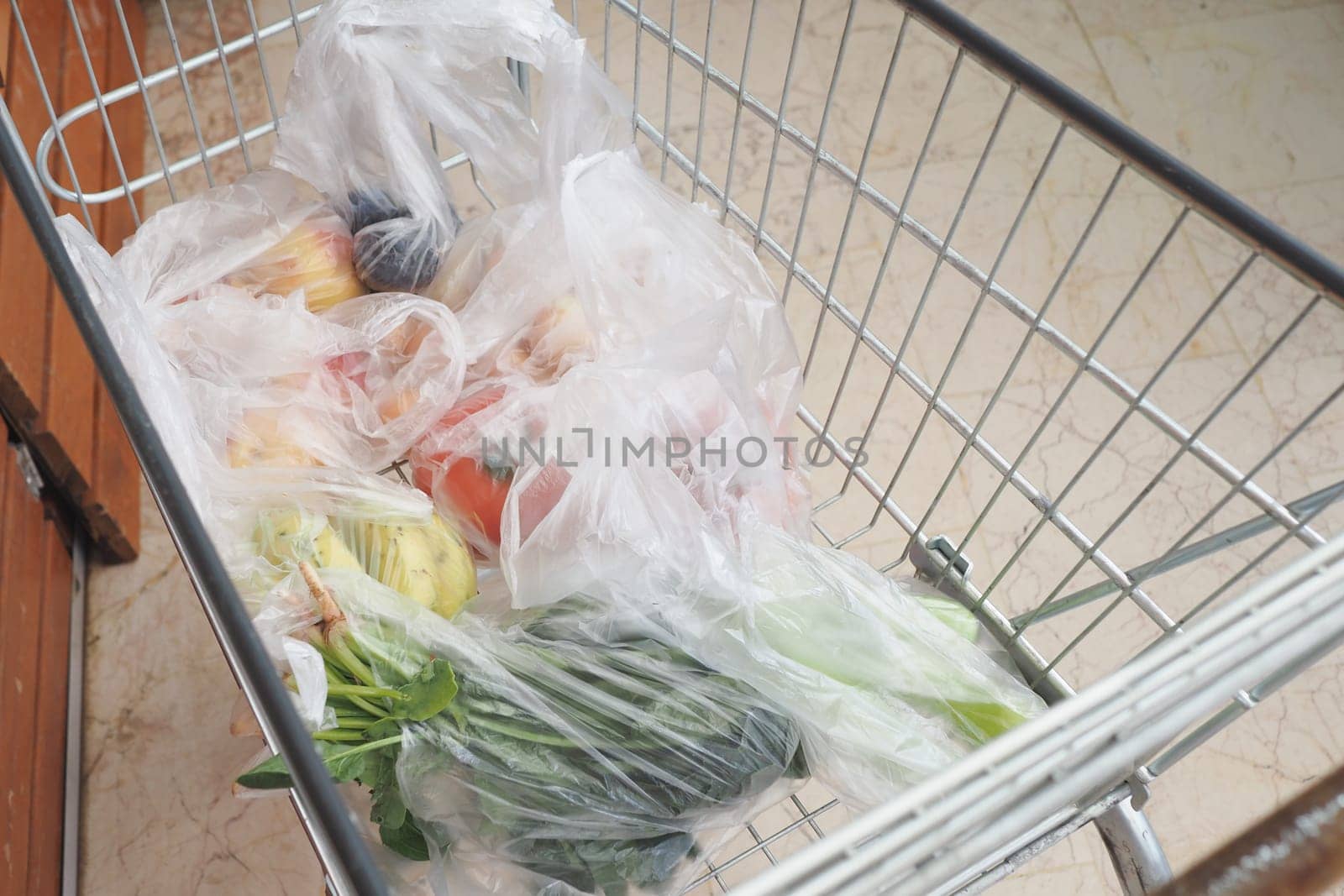 A grocery cart full of vibrant, fresh fruits and wholesome vegetables in clear bags