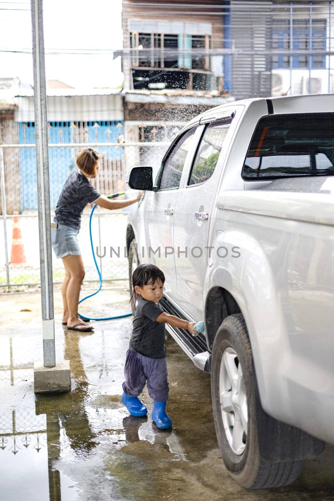 Little child Help his mother washing family car.