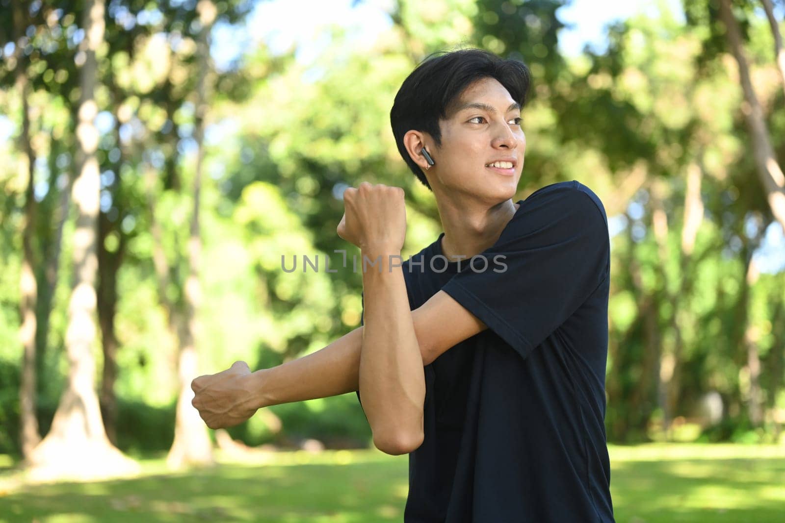 Man runner stretching in the park on a sunny day. Heath and fitness concept.