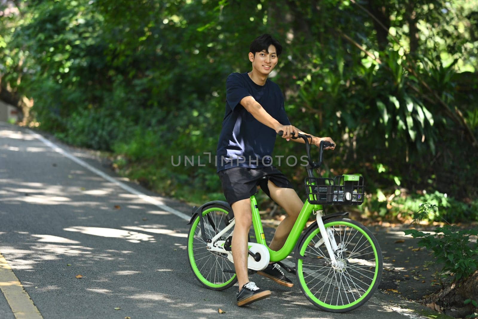 Happy young man is riding a bicycle on a sunny path through the trees..
