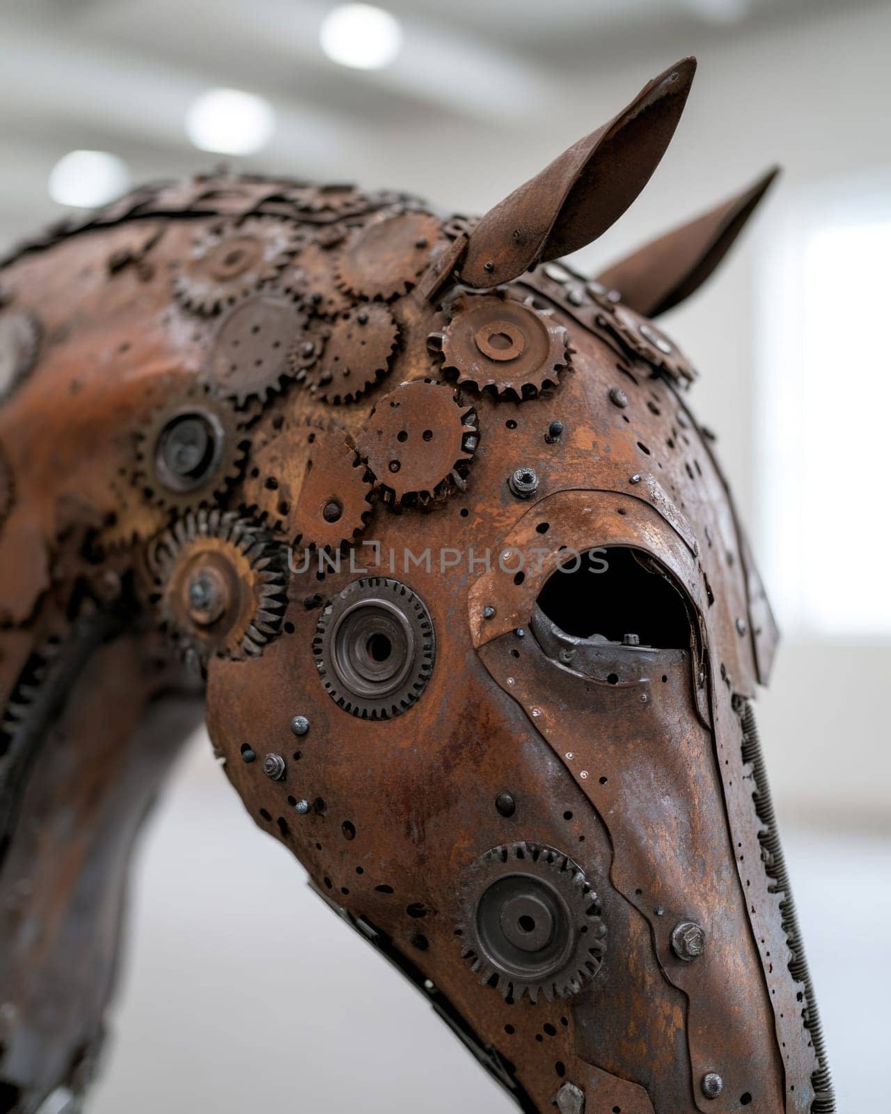 A striking sculpture of a horse fashioned from gears and metal pieces is showcased in a contemporary art gallery. The intricate detailing highlights craftsmanship and creativity.