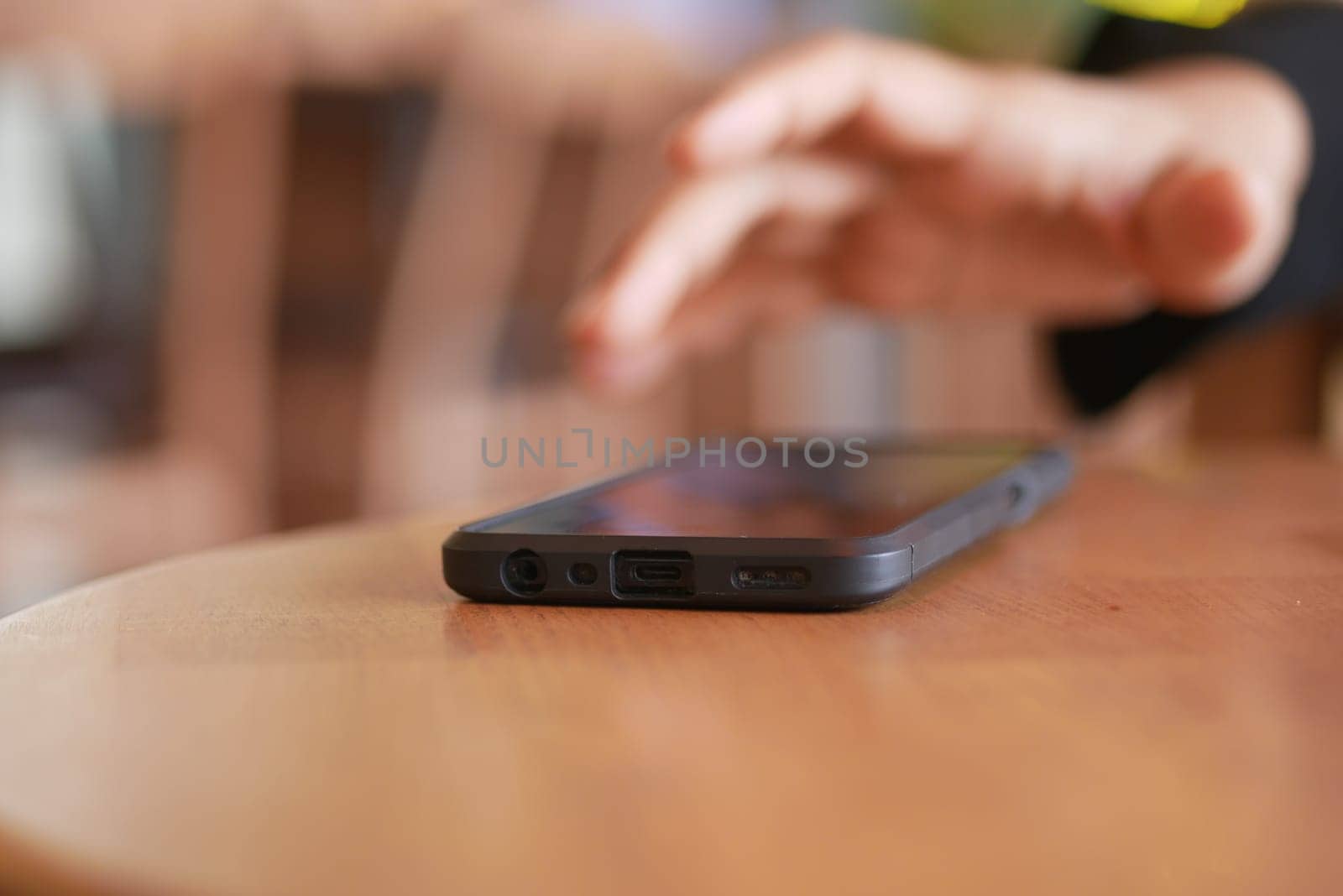 man hand picking up smart phone mobile from a table